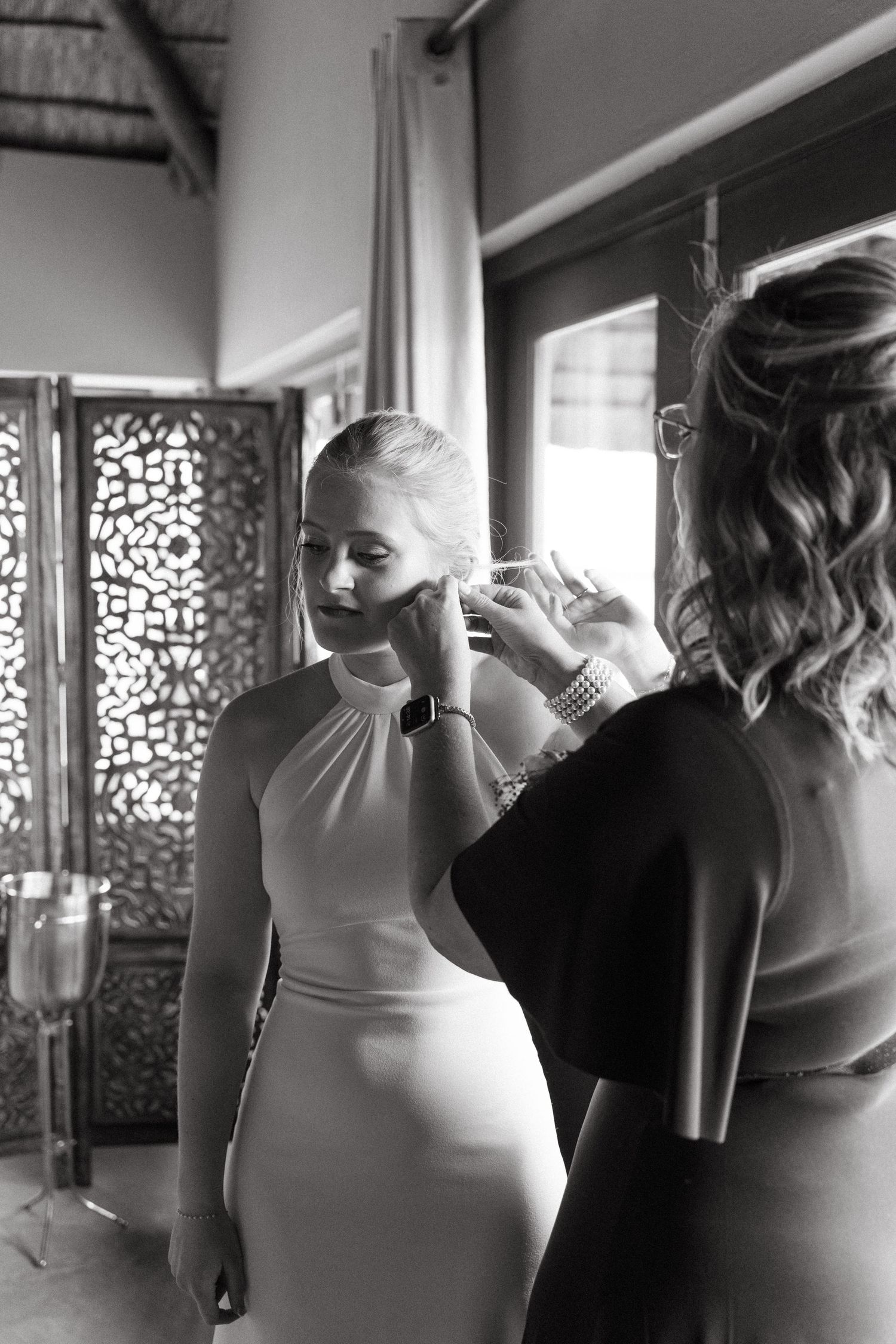 Black and white photo of wedding preparations with women in white dresses getting ready.