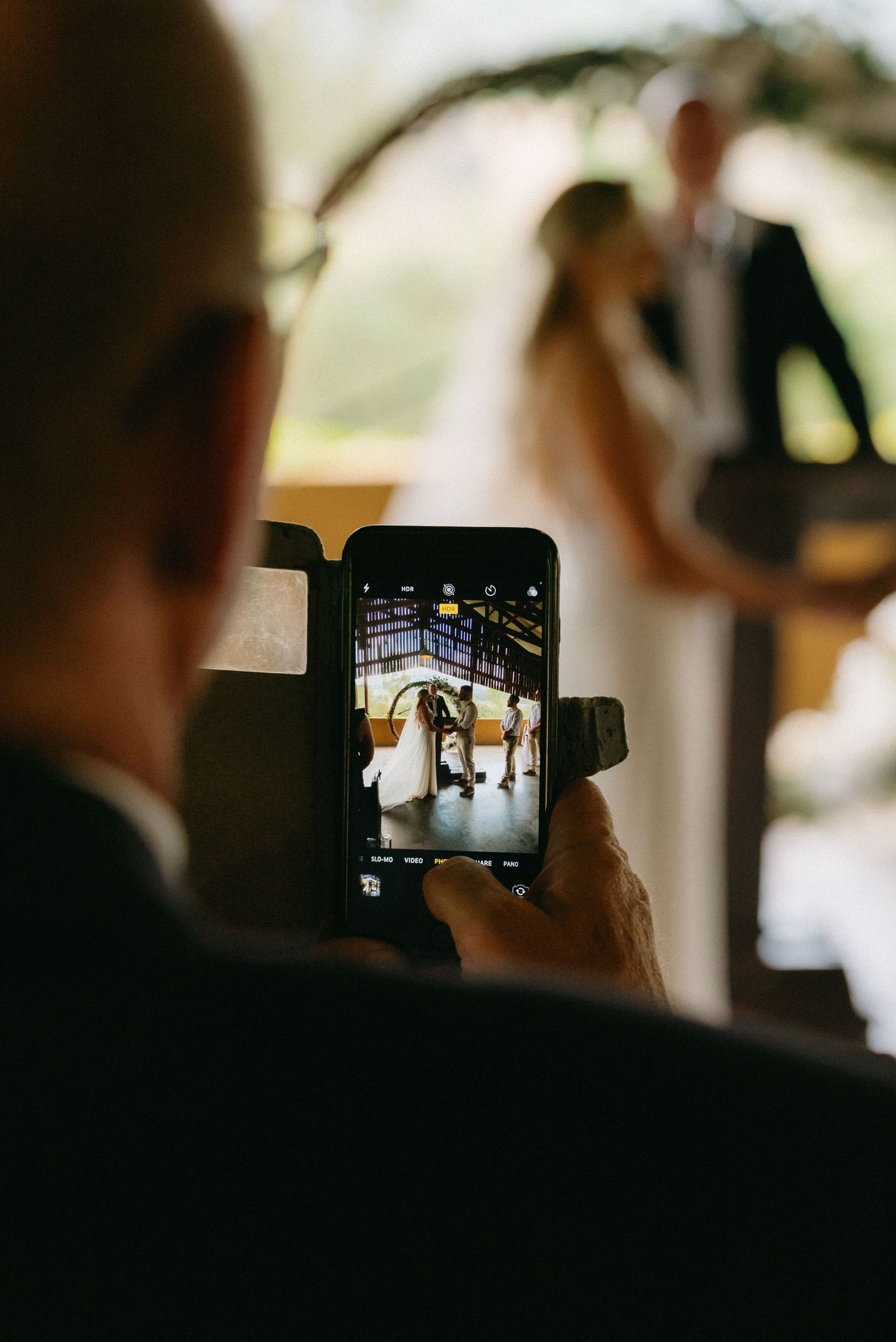 Silhouettes of guests taking photos on phones during an indoor event.
