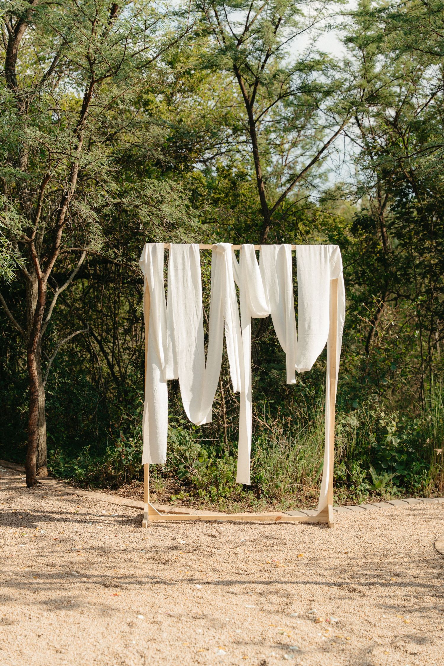 White sheets and linens hanging to dry on clotheslines between trees in a natural outdoor setting.