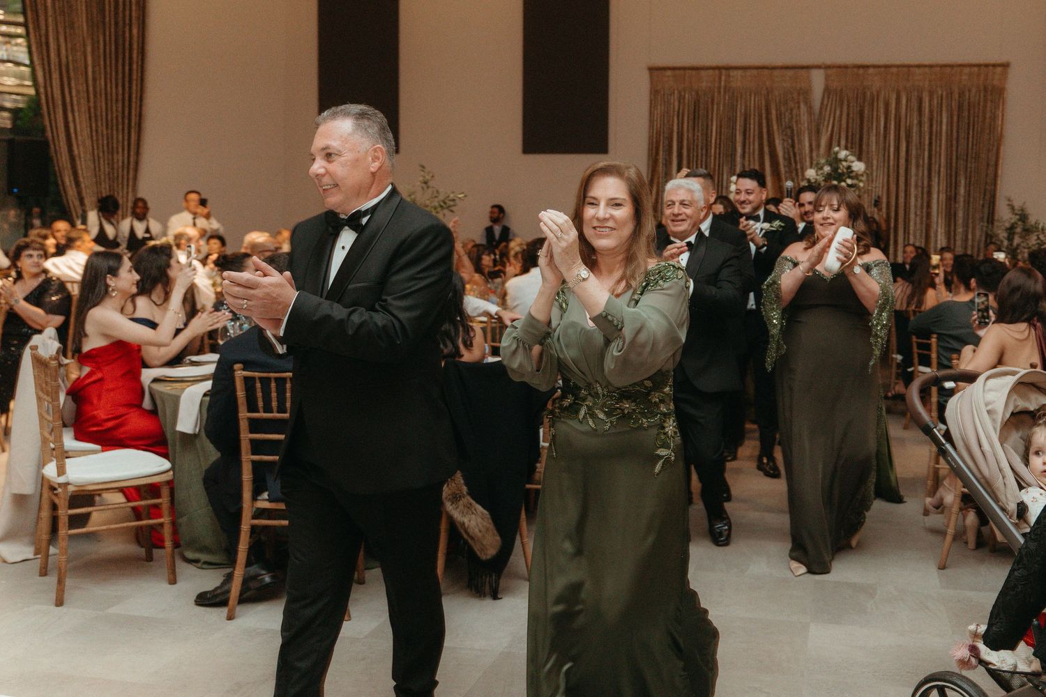 Guests clapping and celebrating at an elegant wedding reception in a formal venue.