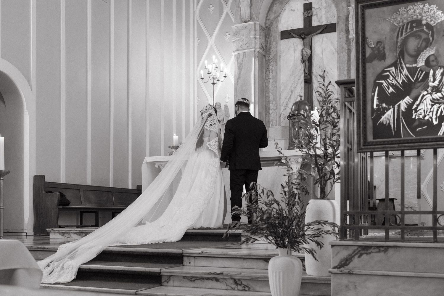 Black and white photo of a bride and groom kneeling at the altar during a church wedding ceremony.