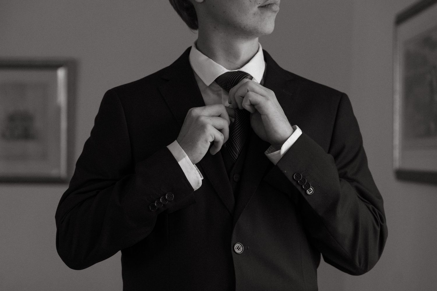 Professional in a dark suit and tie poses thoughtfully with hand on chin in black and white portrait.