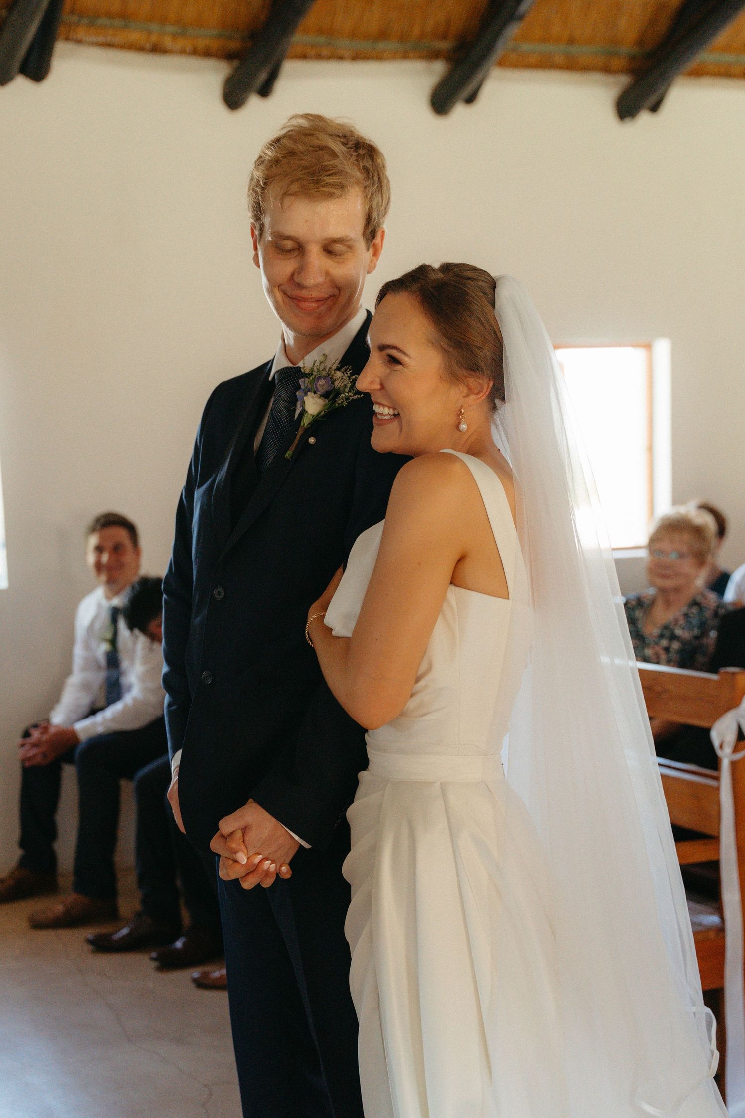 A joyful wedding ceremony moment captured in a church as the couple shares a laugh during their vows.