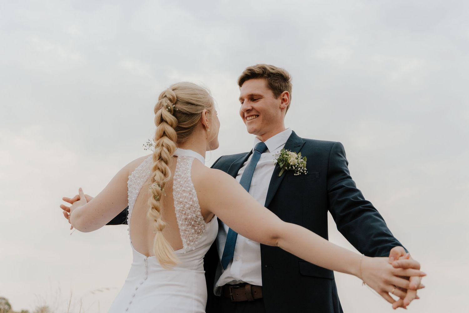 Newlyweds share a romantic moment in an open field during their wedding photoshoot.