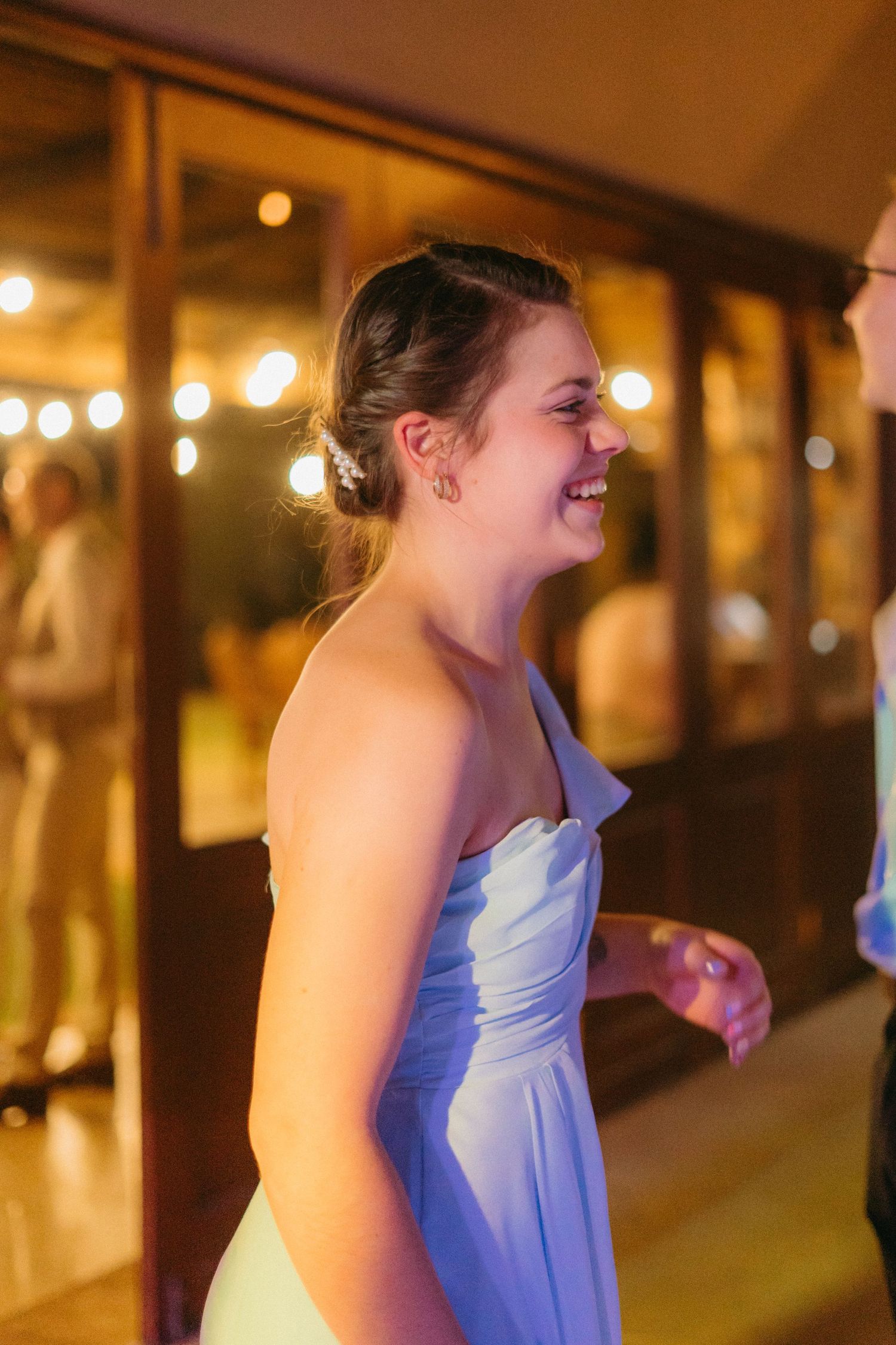 Wedding reception guests dancing and celebrating under warm ambient lighting.