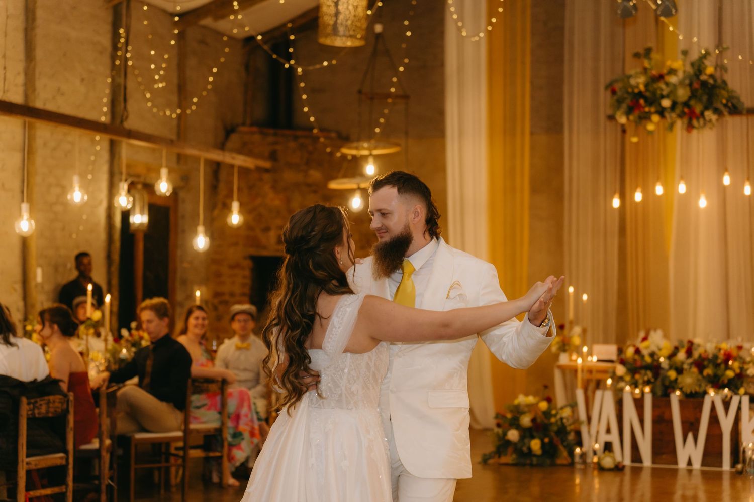 Dance in elegant venue with hanging lights and floral decorations.