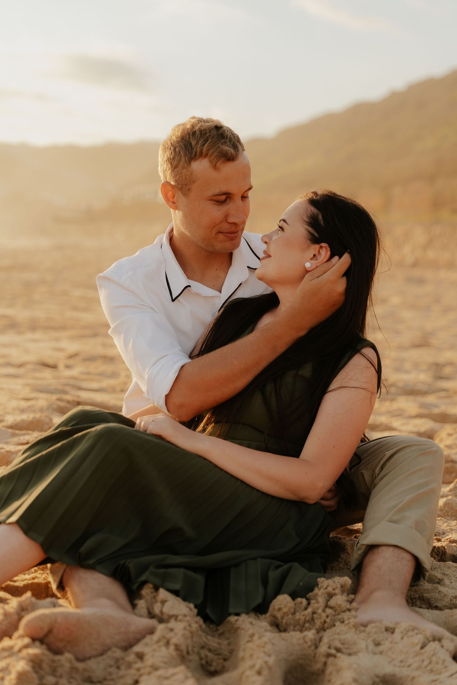 A romantic couple shares intimate moments on a sandy beach at sunset in the Western Cape, South Africa