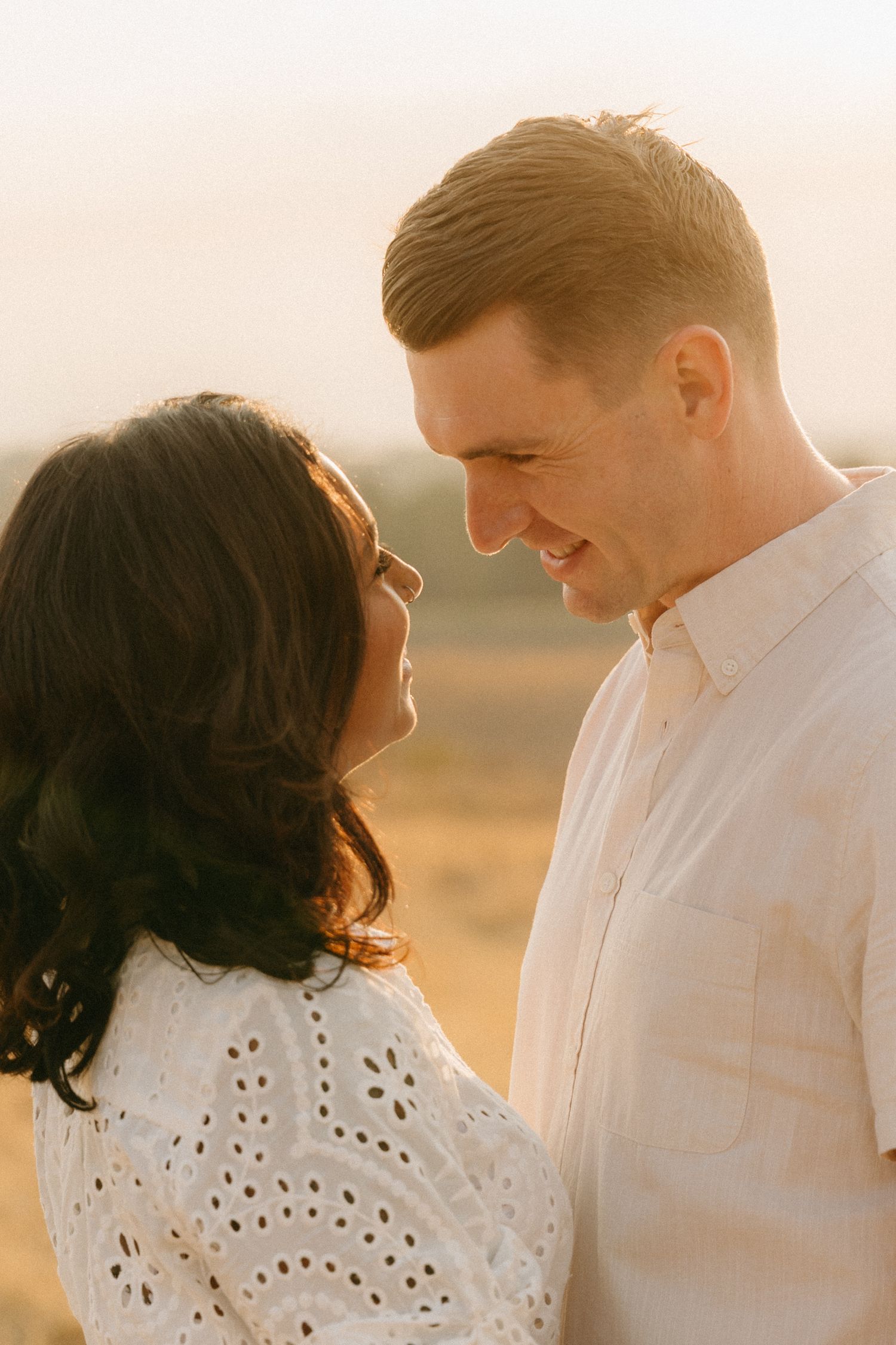 Romantic couple sharing tender moments in a golden wheat field at sunset.