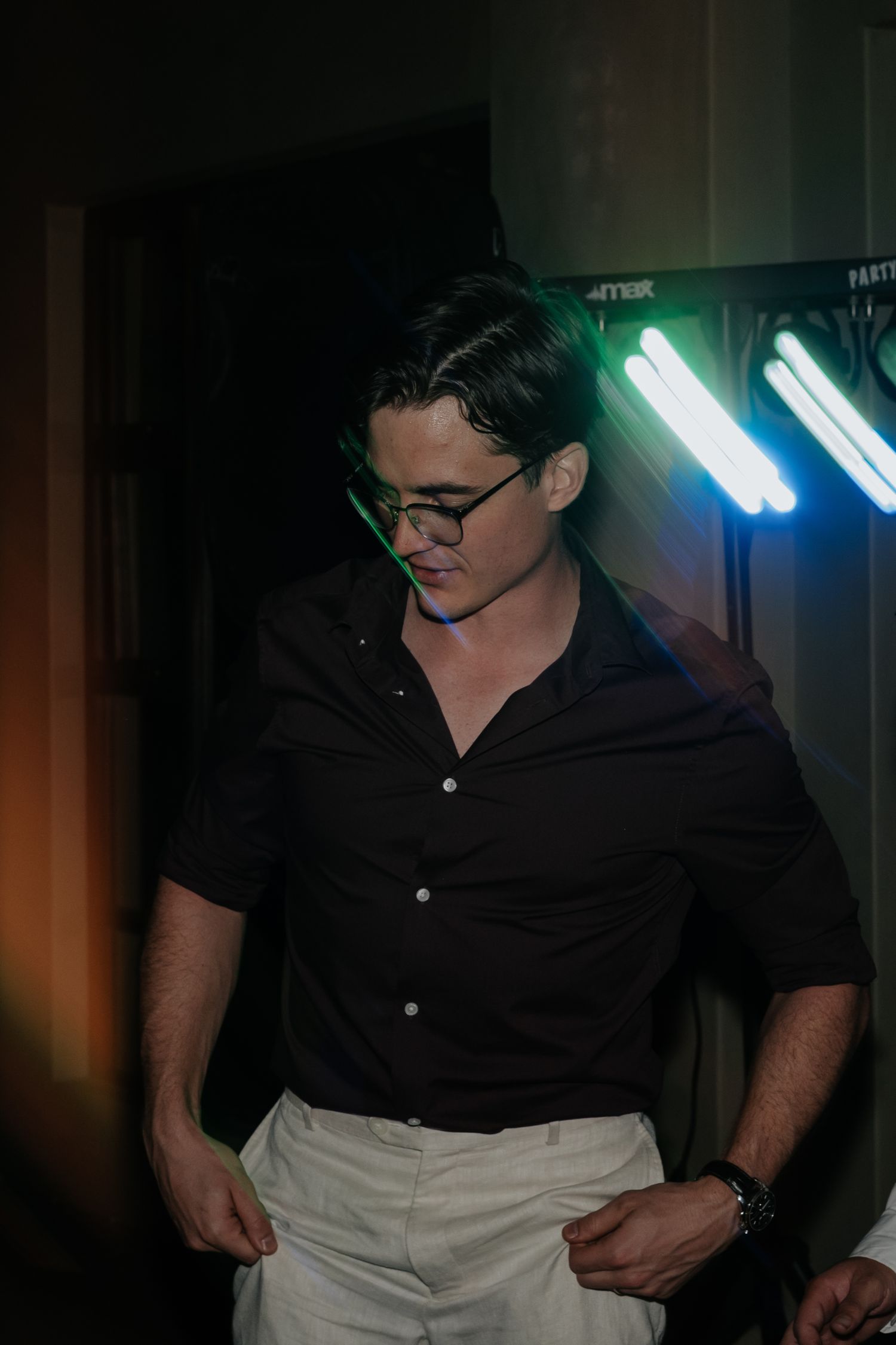 Person in black shirt and light pants dancing energetically in dim lighting.