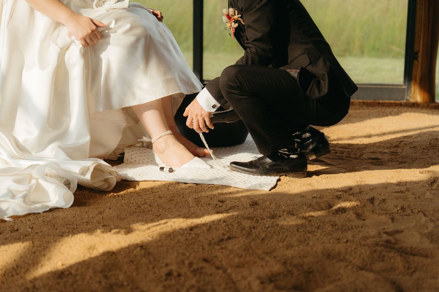A candid moment showing formal attire and shoes on a sunlit wooden floor.