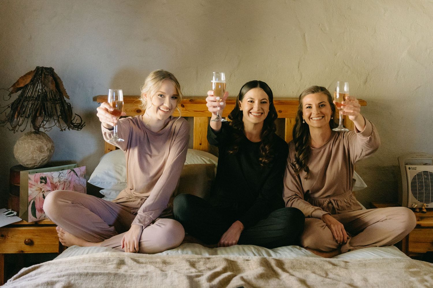 Wedding party relaxing and celebrating together in matching mauve outfits.