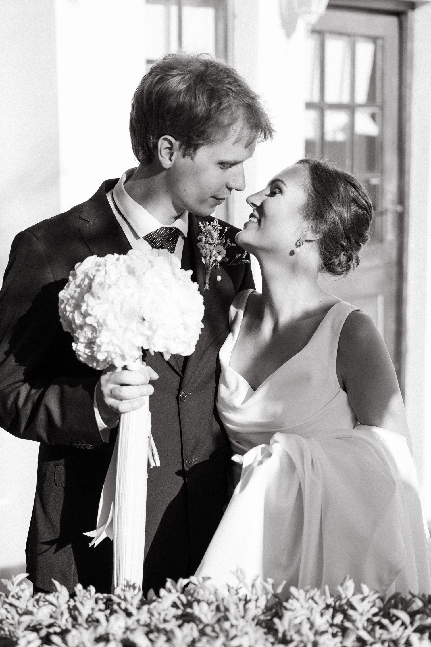 A romantic black and white wedding photo sequence showing a couple sharing tender kisses with white floral decorations.