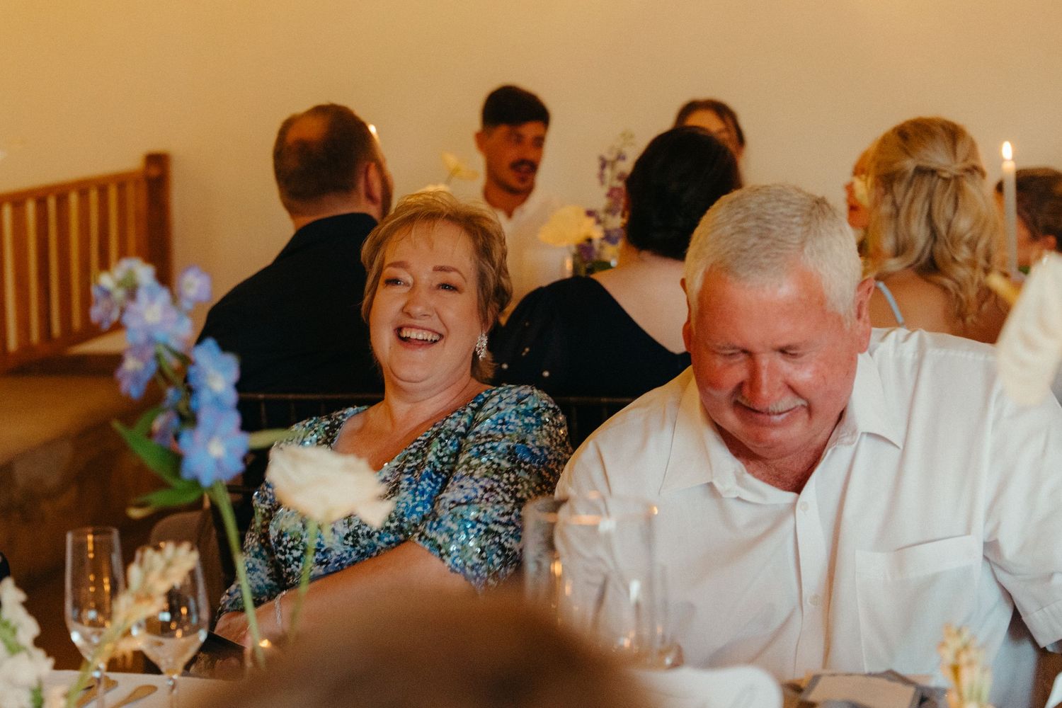 A group of people laughing and enjoying themselves at a formal dinner event.