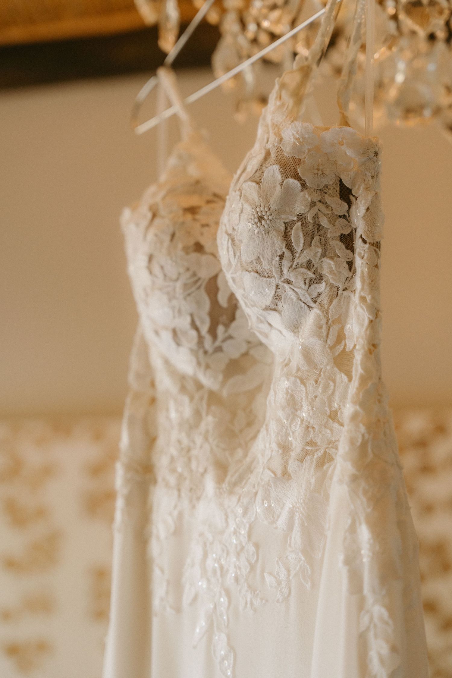 White lace wedding dresses hang in a row showing intricate detail and craftsmanship.