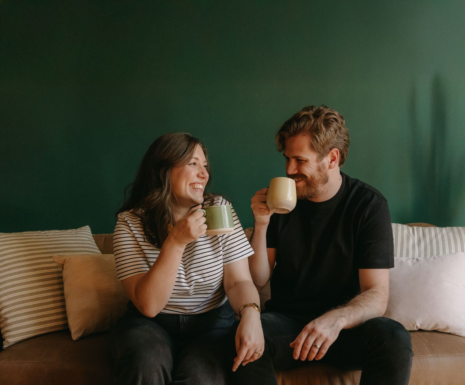 A series of candid photos showing a couple laughing and interacting together on a couch with dark green walls in background.