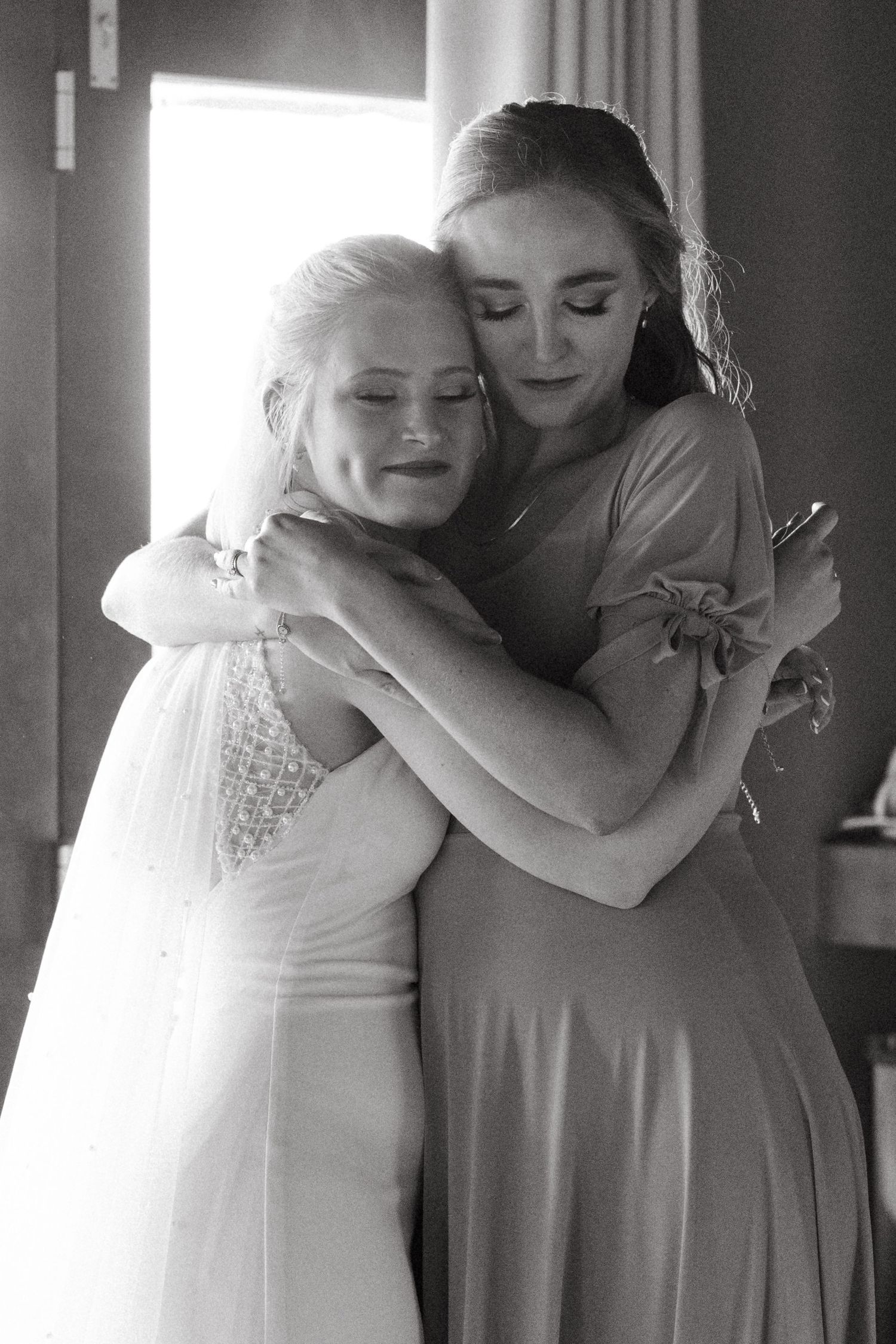 Emotional black and white photo of wedding party sharing embraces before the ceremony.