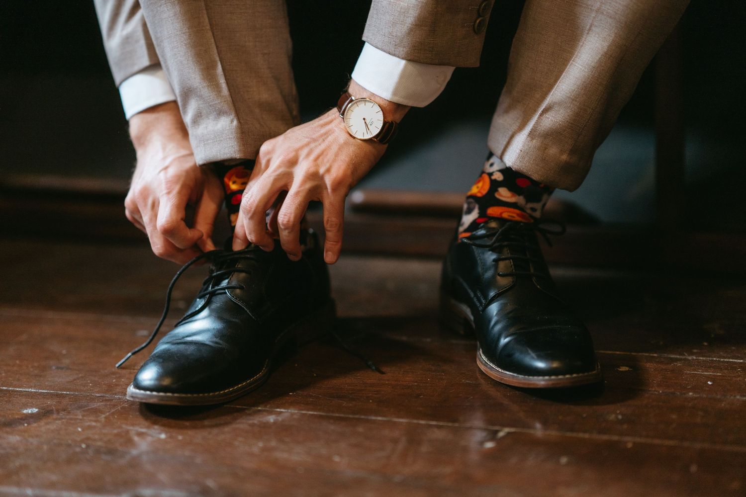 Close-up of groom's hands tying formal black dress shoes.