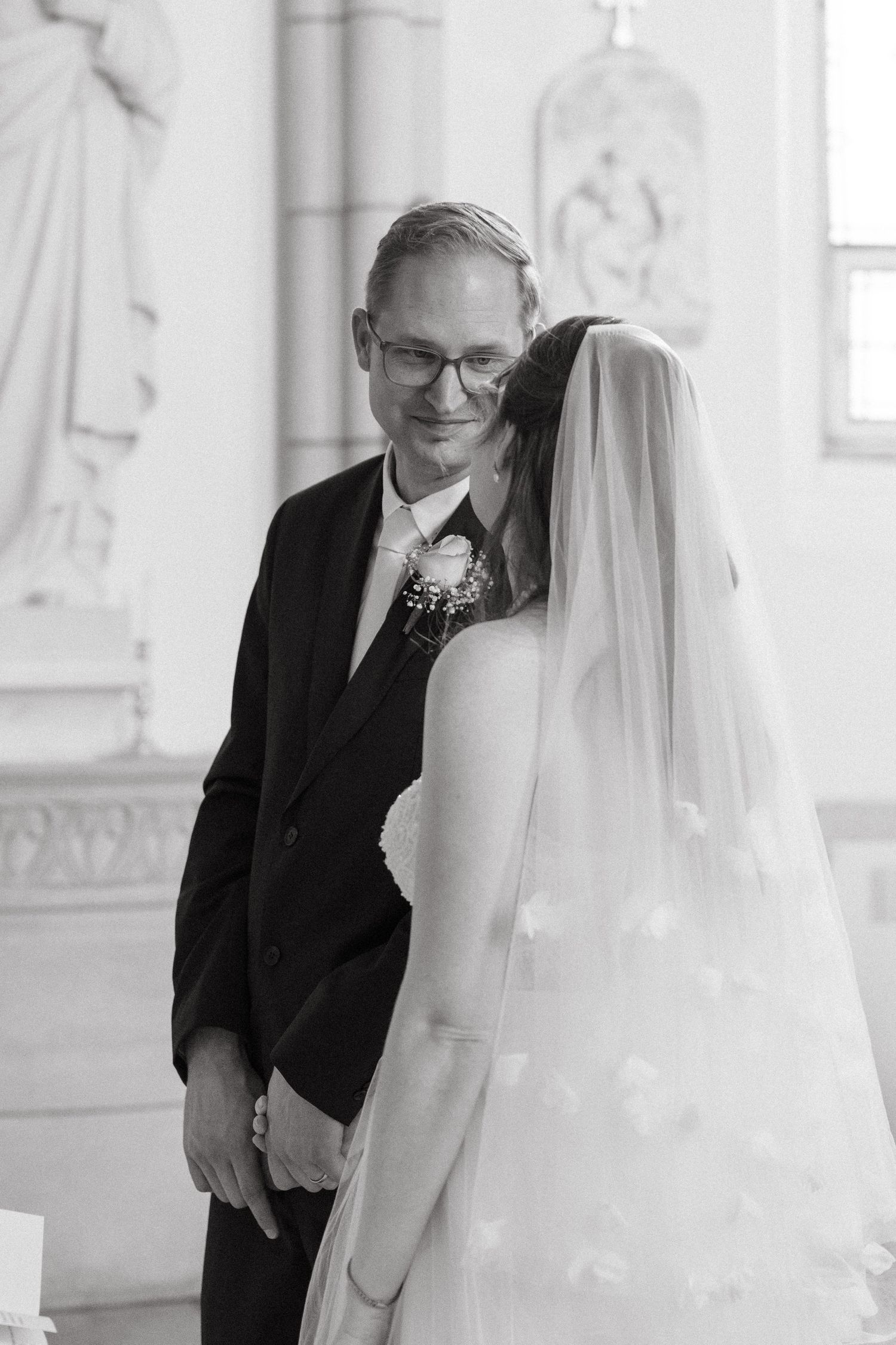 A tender moment between a bride in white and her groom in formal wear at a wedding ceremony.