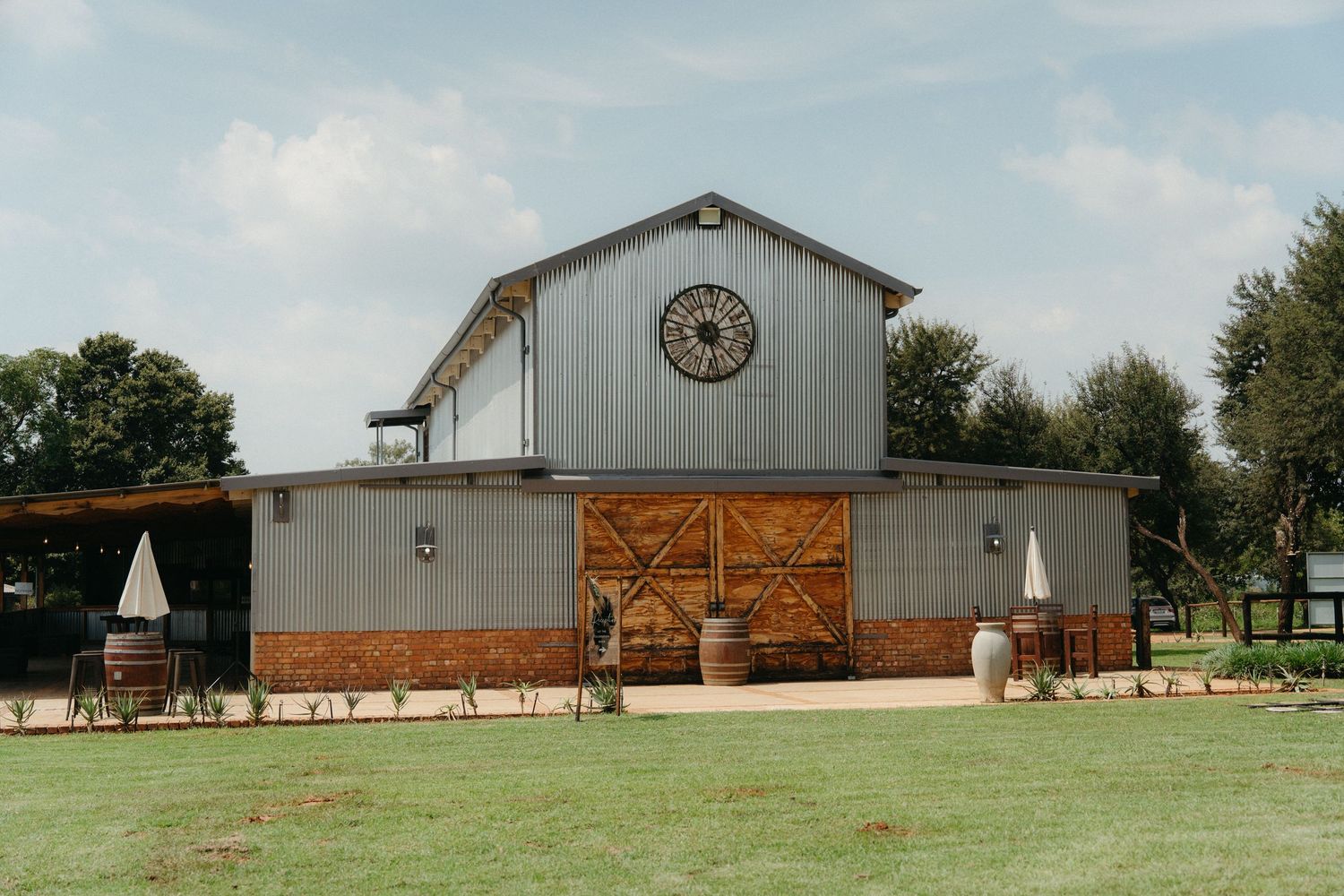 Modern rustic barn wedding venue with white siding and wooden accents set against a blue summer sky.