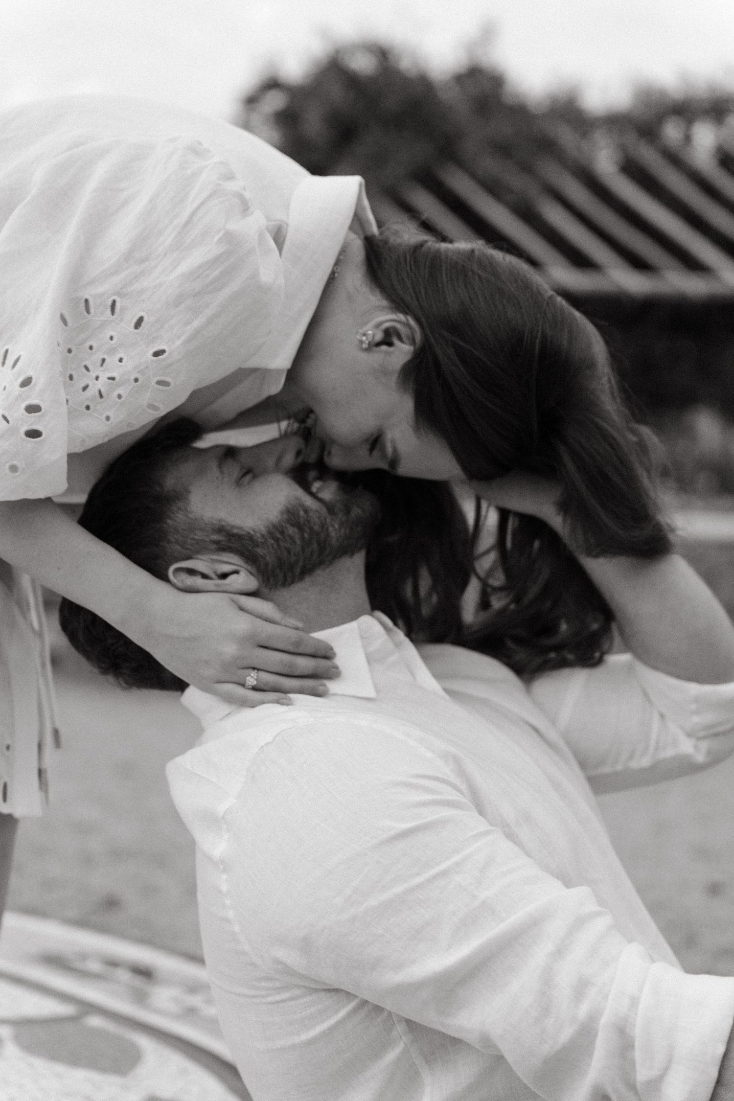 Black and white photo of intimate couple embracing outdoors in romantic pose.