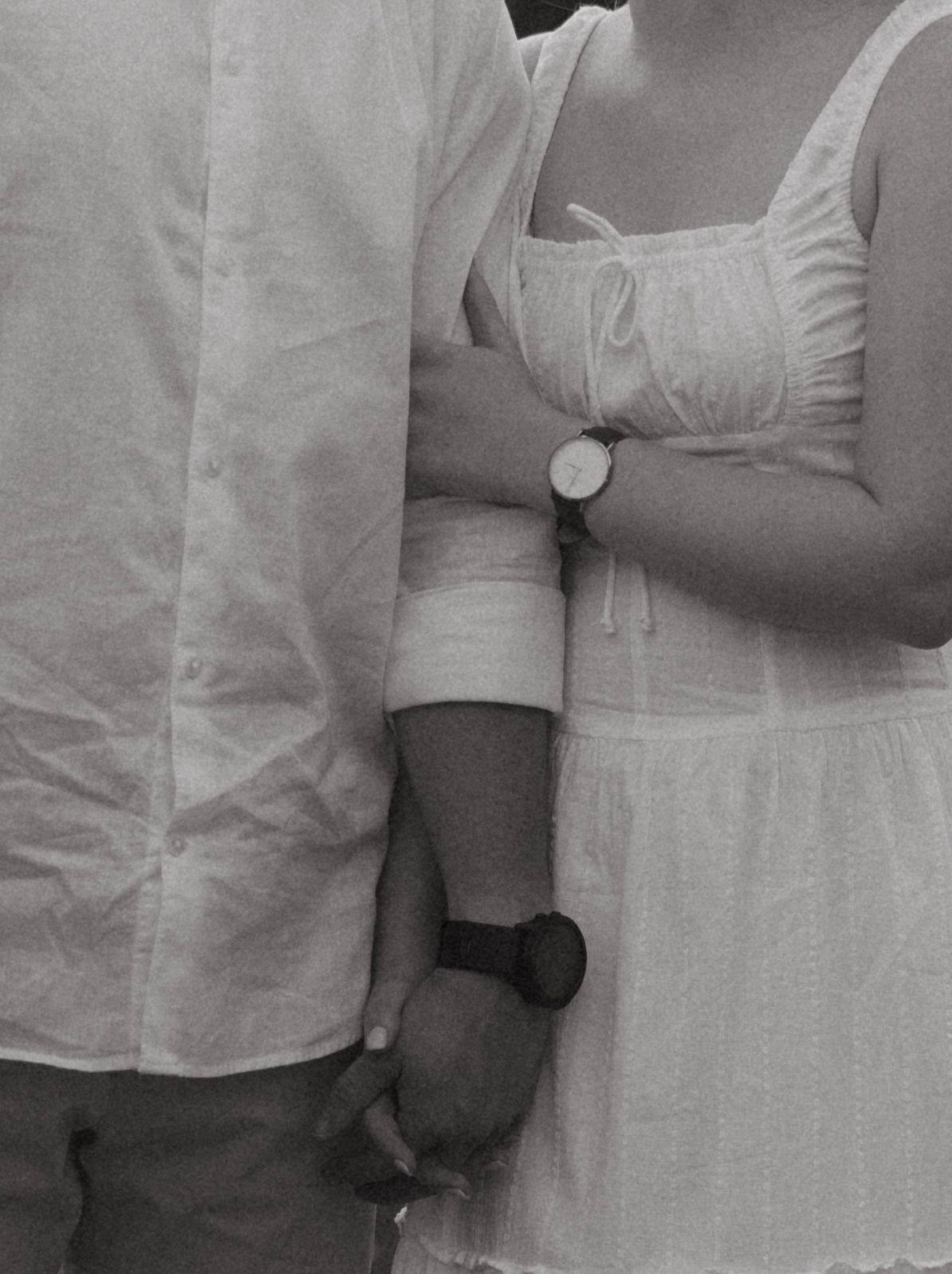 Close-up detail of couple's matching white outfits and watches.