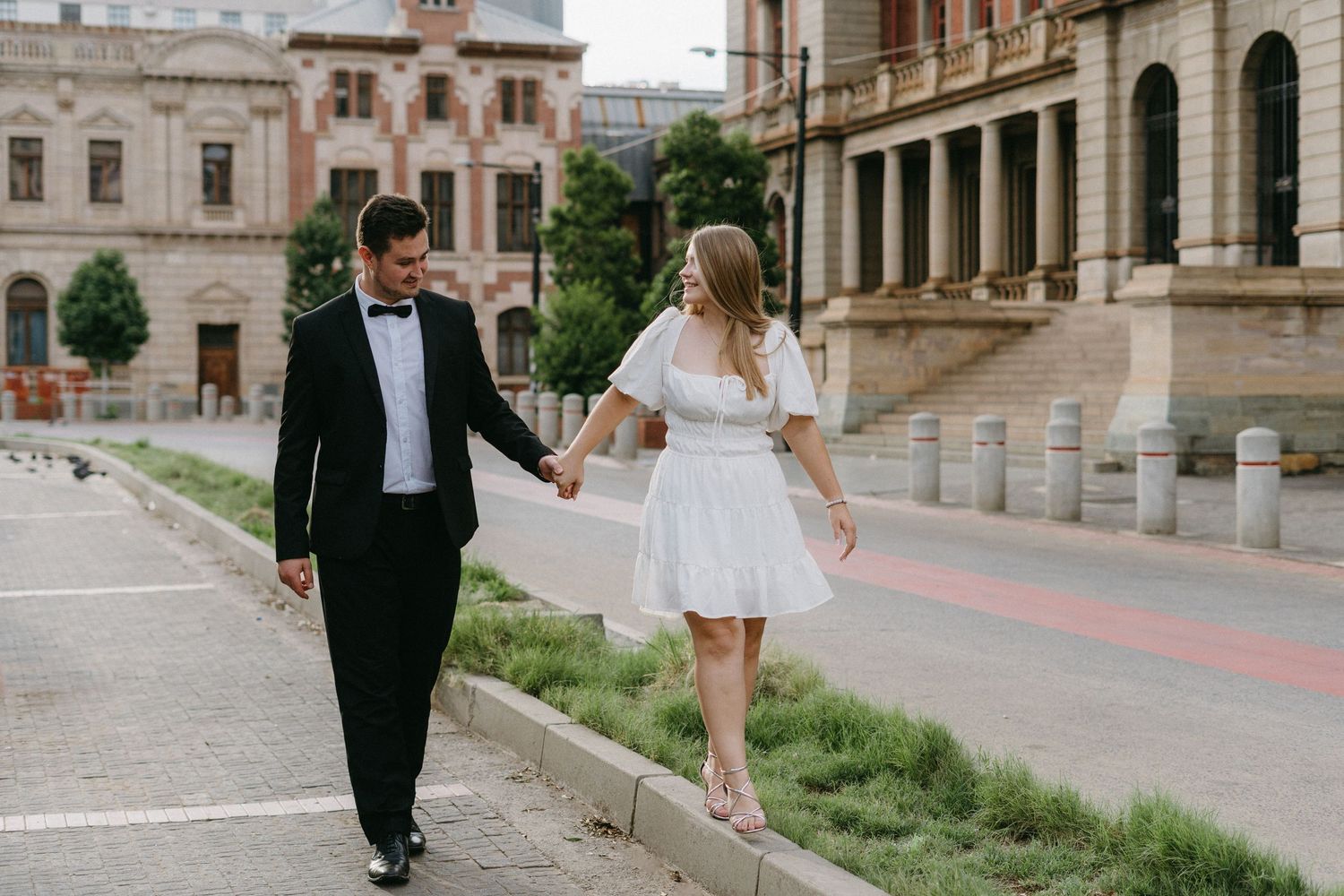 Couple shares a romantic moment on a scenic overlook with cityscape views in the background.