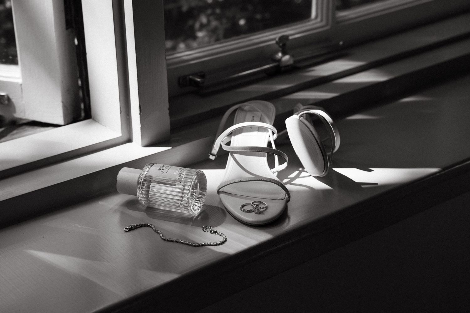Black and white photo of headphones and a water bottle on a sunlit windowsill.