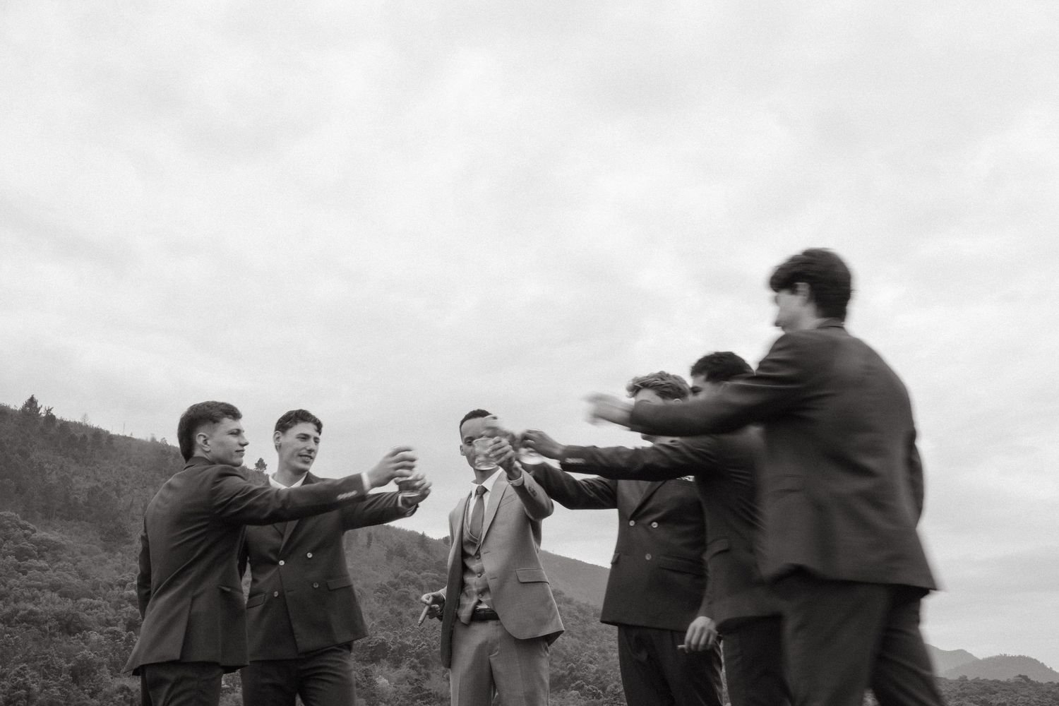 Black and white photo of groomsmen celebrating with the groom outdoors on a cloudy day in Plettenberg Bay.