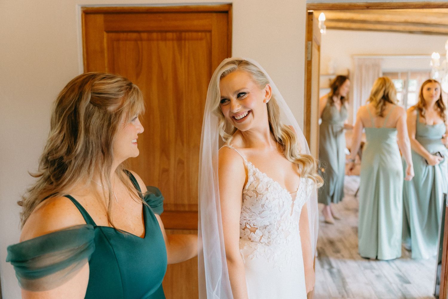 Wedding preparation scene with pastel bridesmaid dresses hanging in a sunlit dressing room.