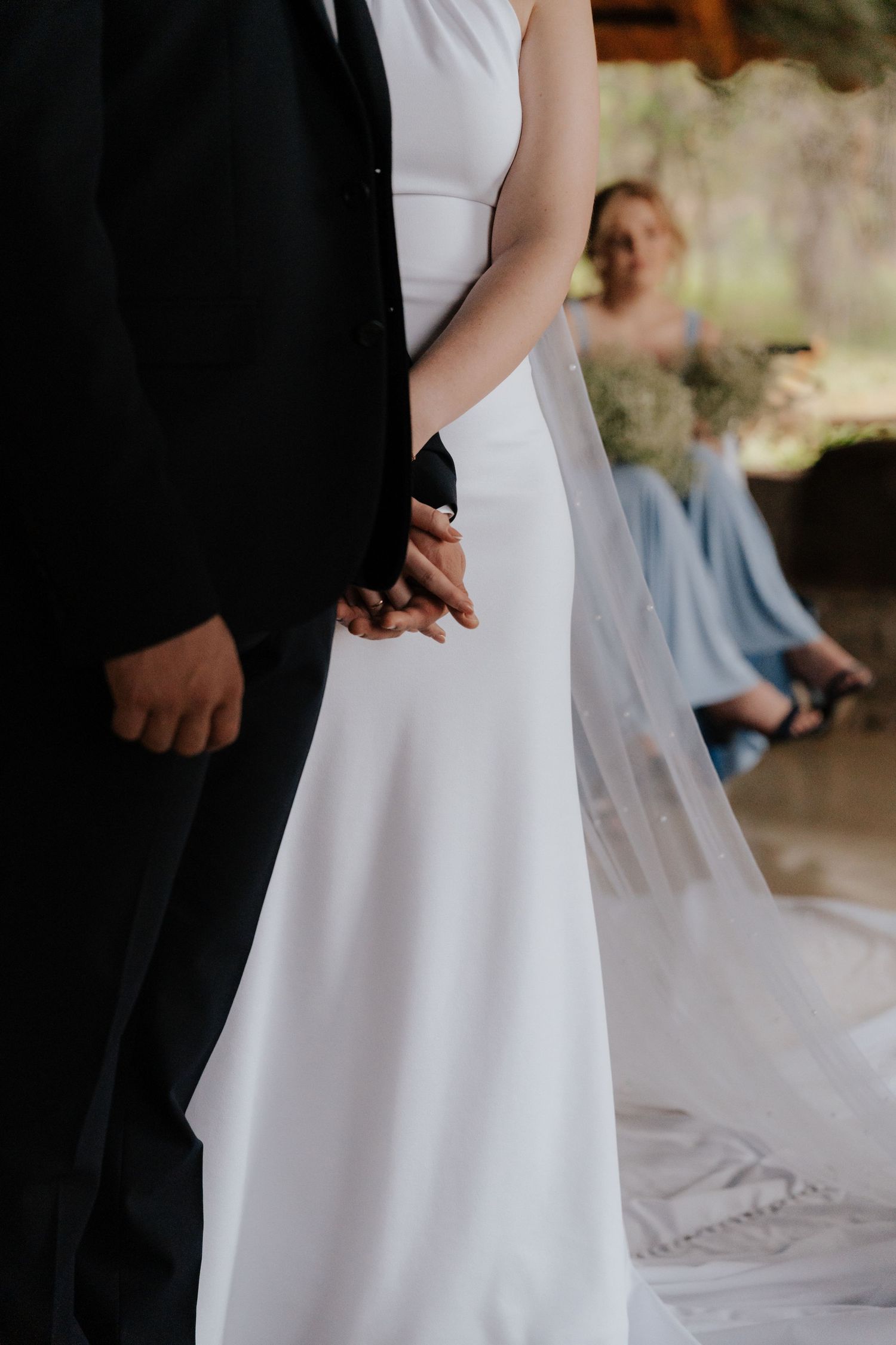 Close-up of wedding attire showing a white dress and black suit during an intimate moment.