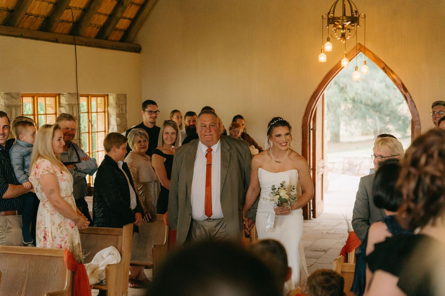 Wedding celebration inside a rustic chapel venue with exposed wooden beams and natural lighting.