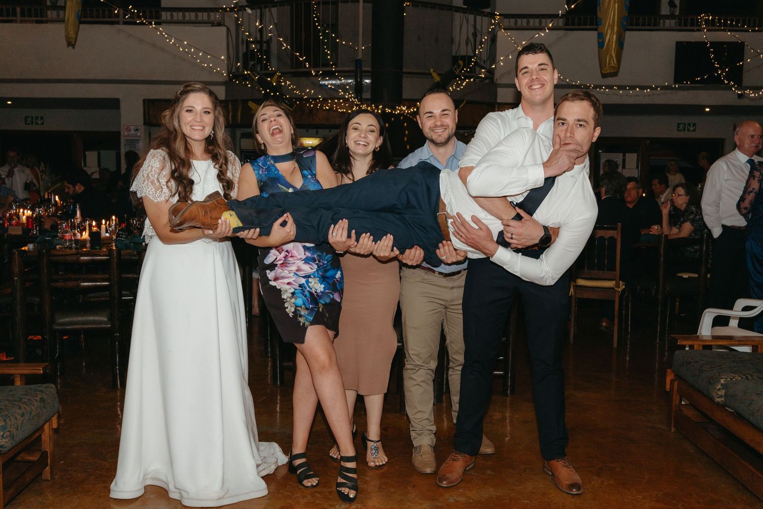 A group photo of wedding guests and the couple posing at a reception venue.