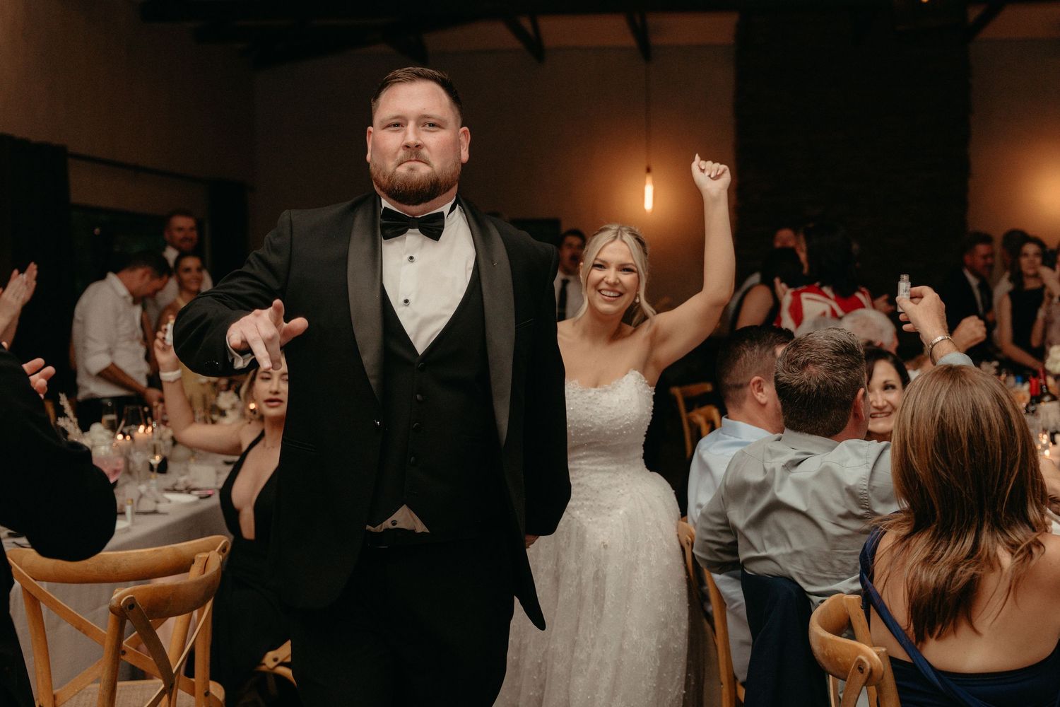 Wedding guests dancing and celebrating together on a dimly lit dance floor at an evening reception.