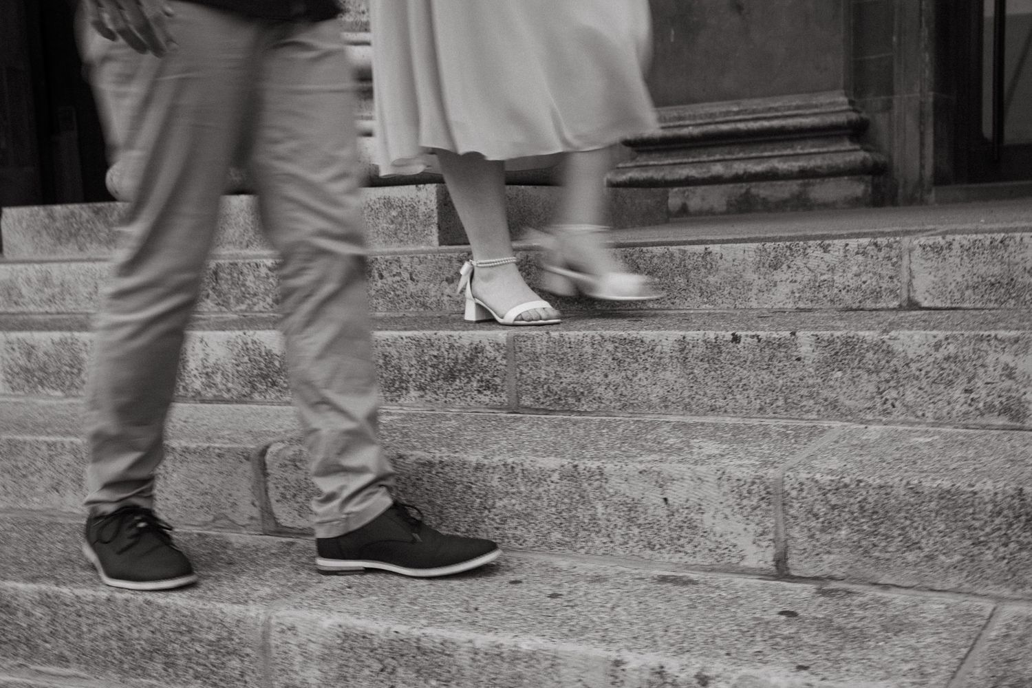 People's feet walking across stone steps in a black and white photograph.