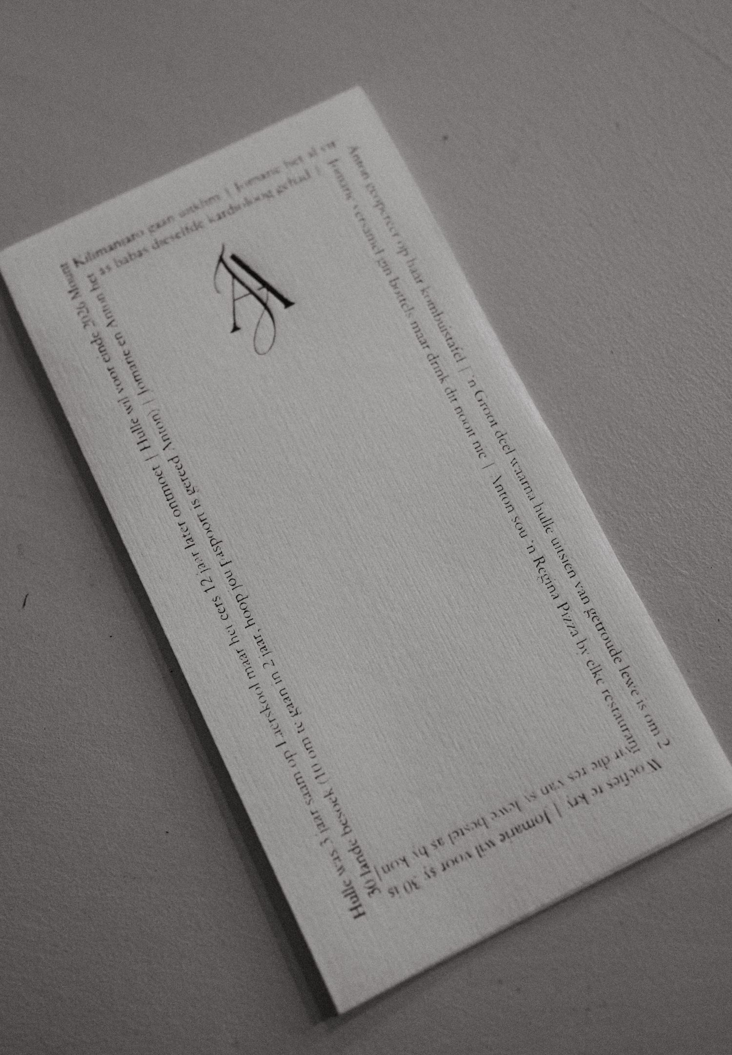 A black and white photograph of a simple envelope or card with text printed around the border.