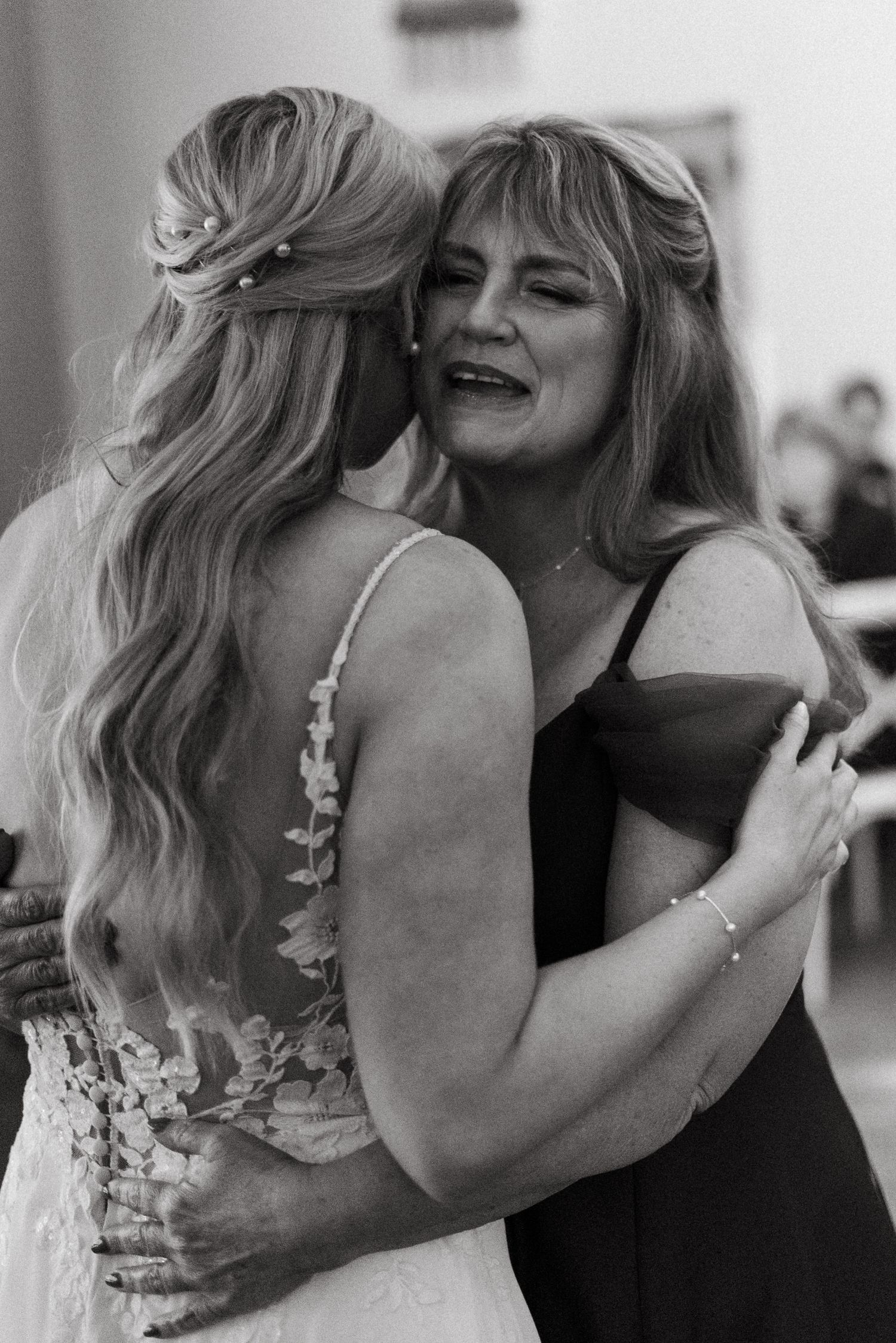 Two wedding guests share an emotional embrace on the dance floor.