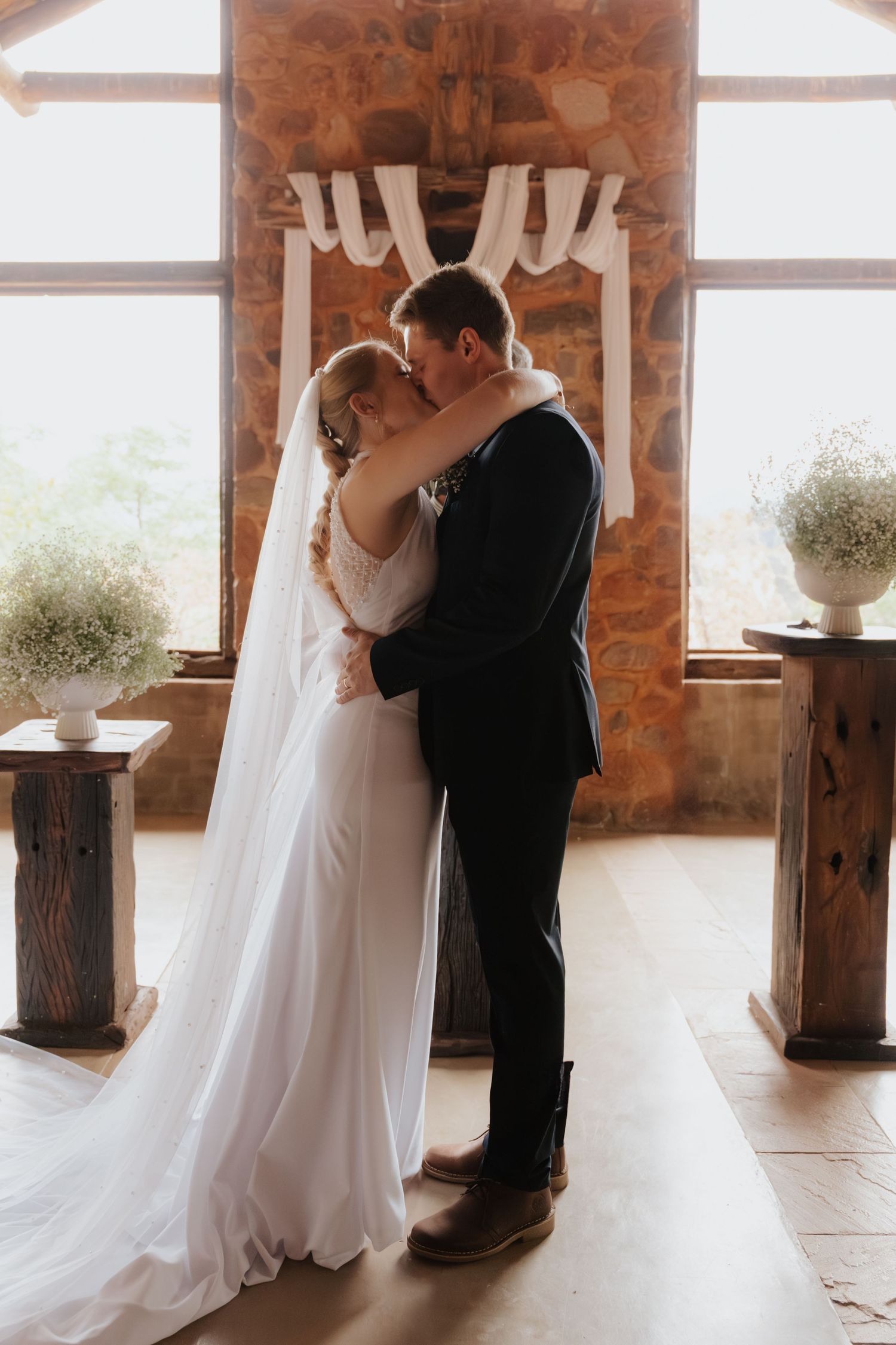 A romantic first dance moment between newlyweds in an elegant stone-walled venue with natural light.