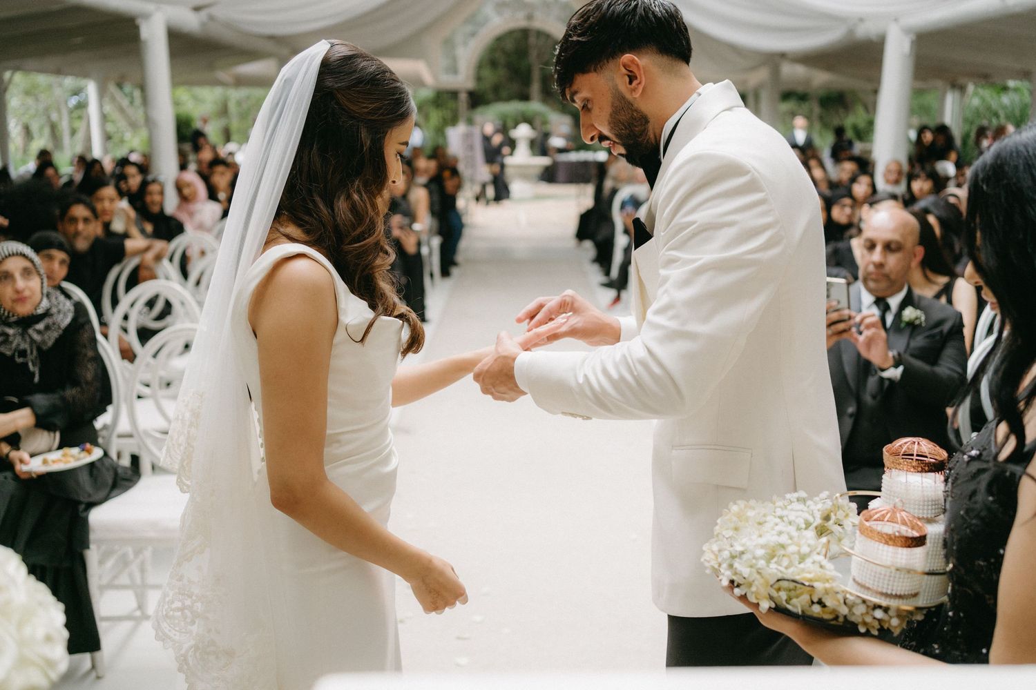 A joyful wedding celebration under a tent with the couple dancing together in white attire.