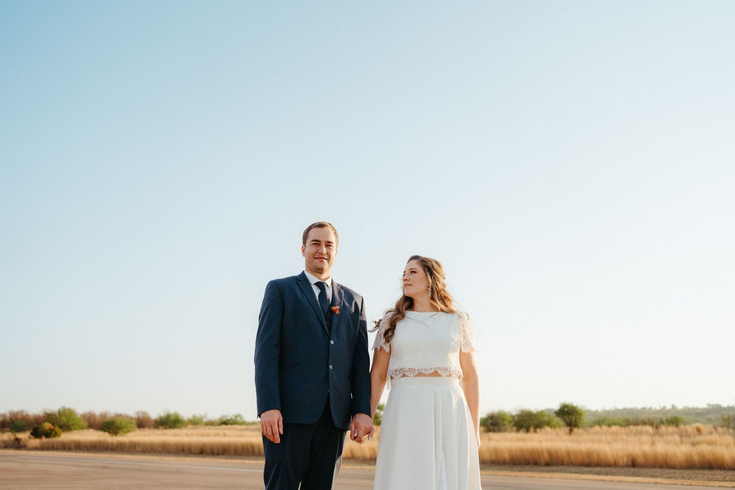 A wedding portrait against a clear blue sky backdrop in an open field.