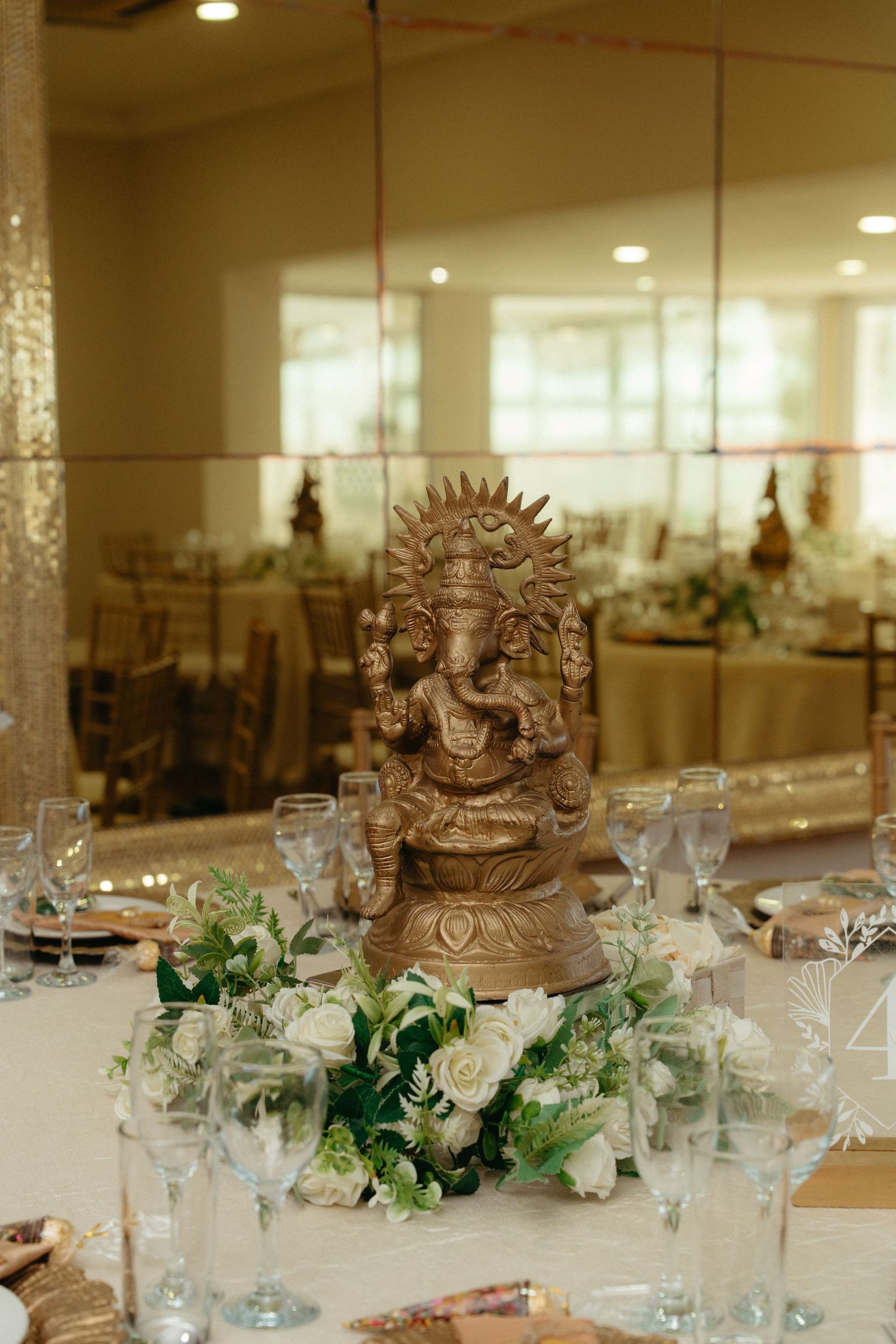 Elegant wedding reception table decorated with white floral centerpieces and ornate brown crown decorations.