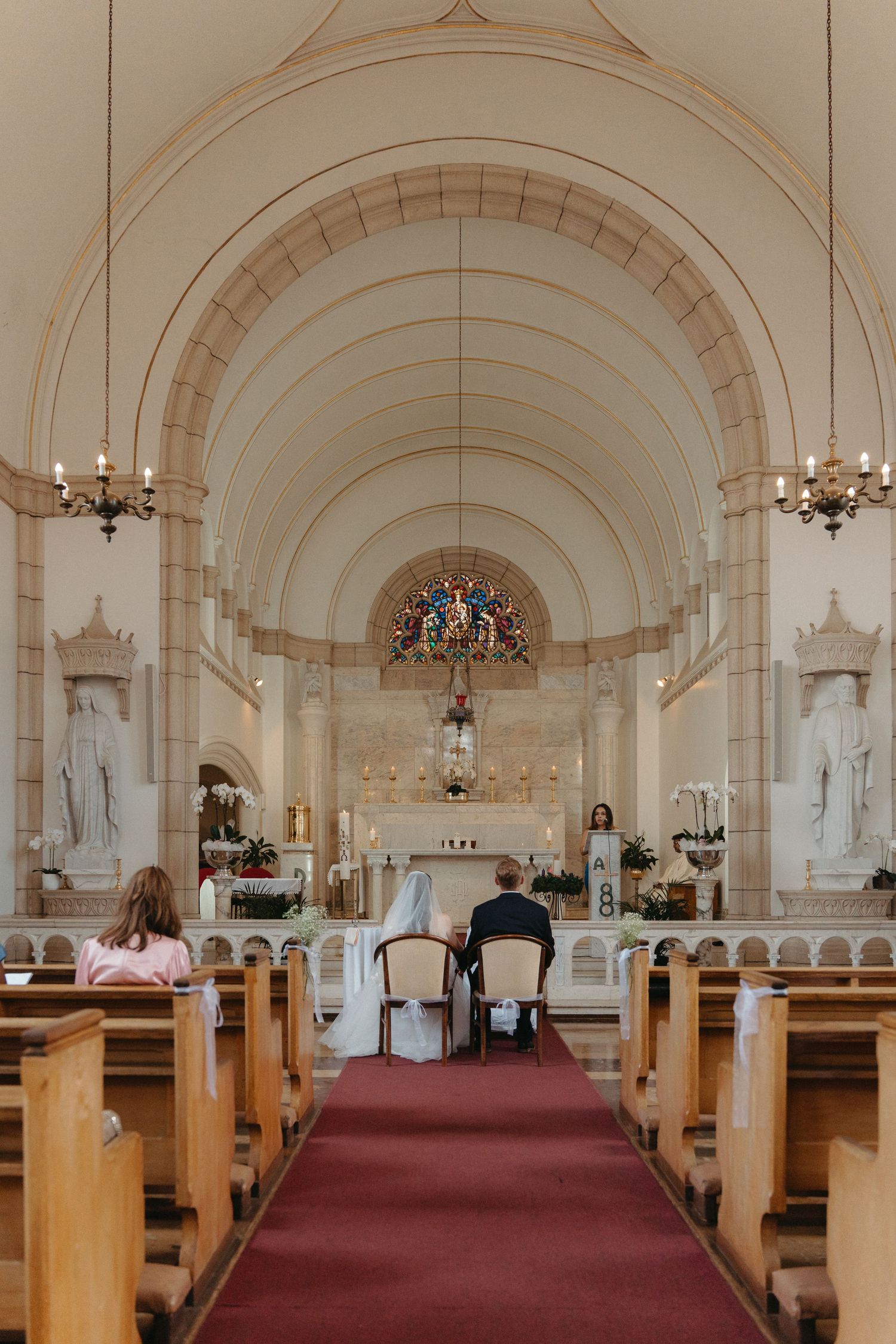 Interior view of Nazareth House Chapel with vaulted ceilings, wooden pews, and a red carpet leading to the altar.