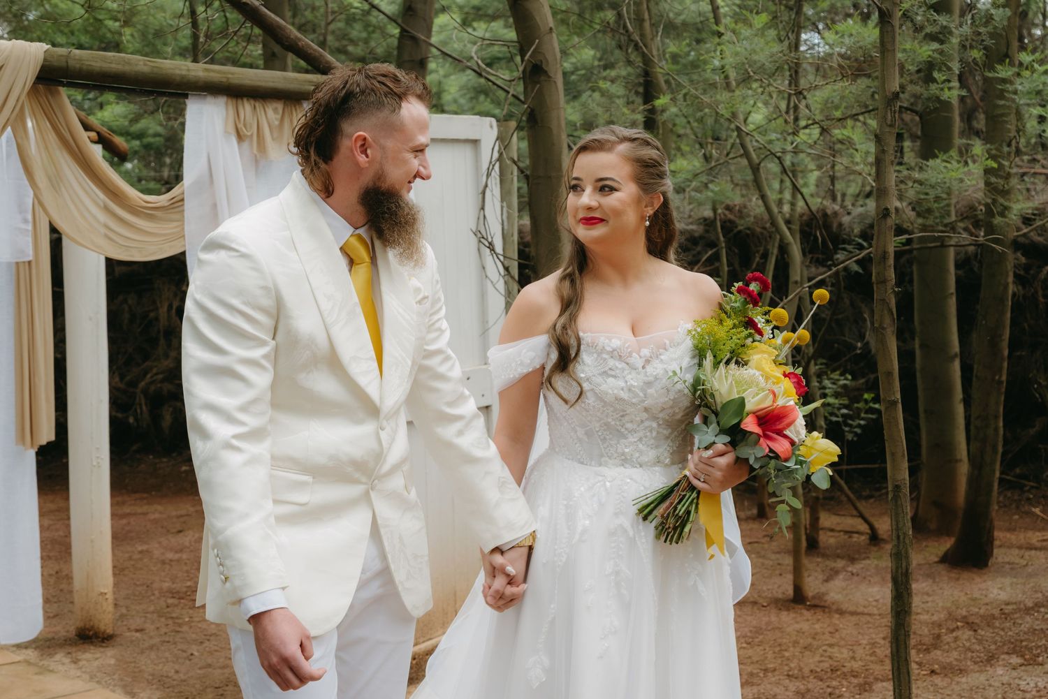 A couple shares a joyful moment during their outdoor forest wedding ceremony.