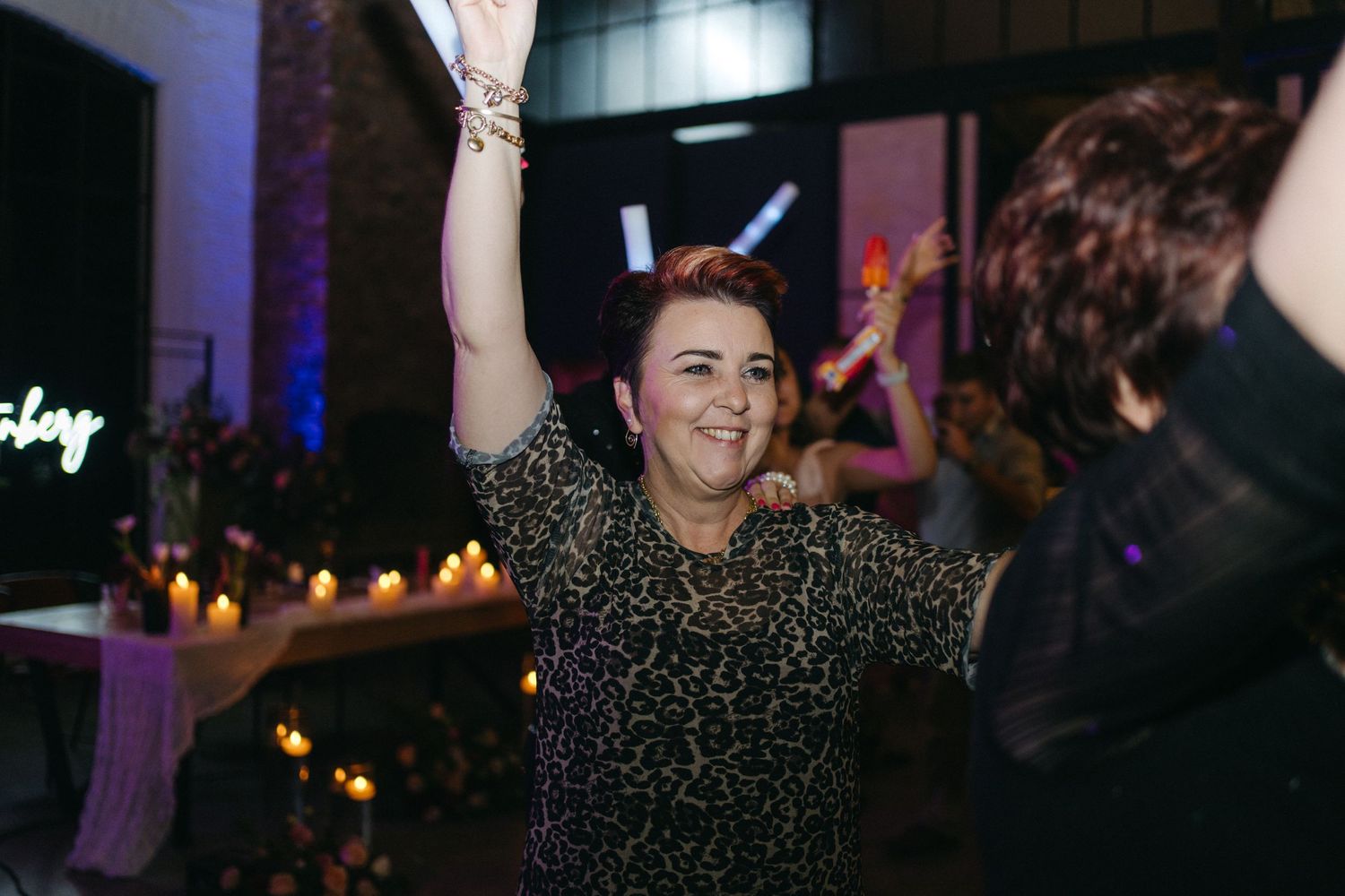 Dancing guest enjoying lively celebration with raised arms at evening wedding reception.