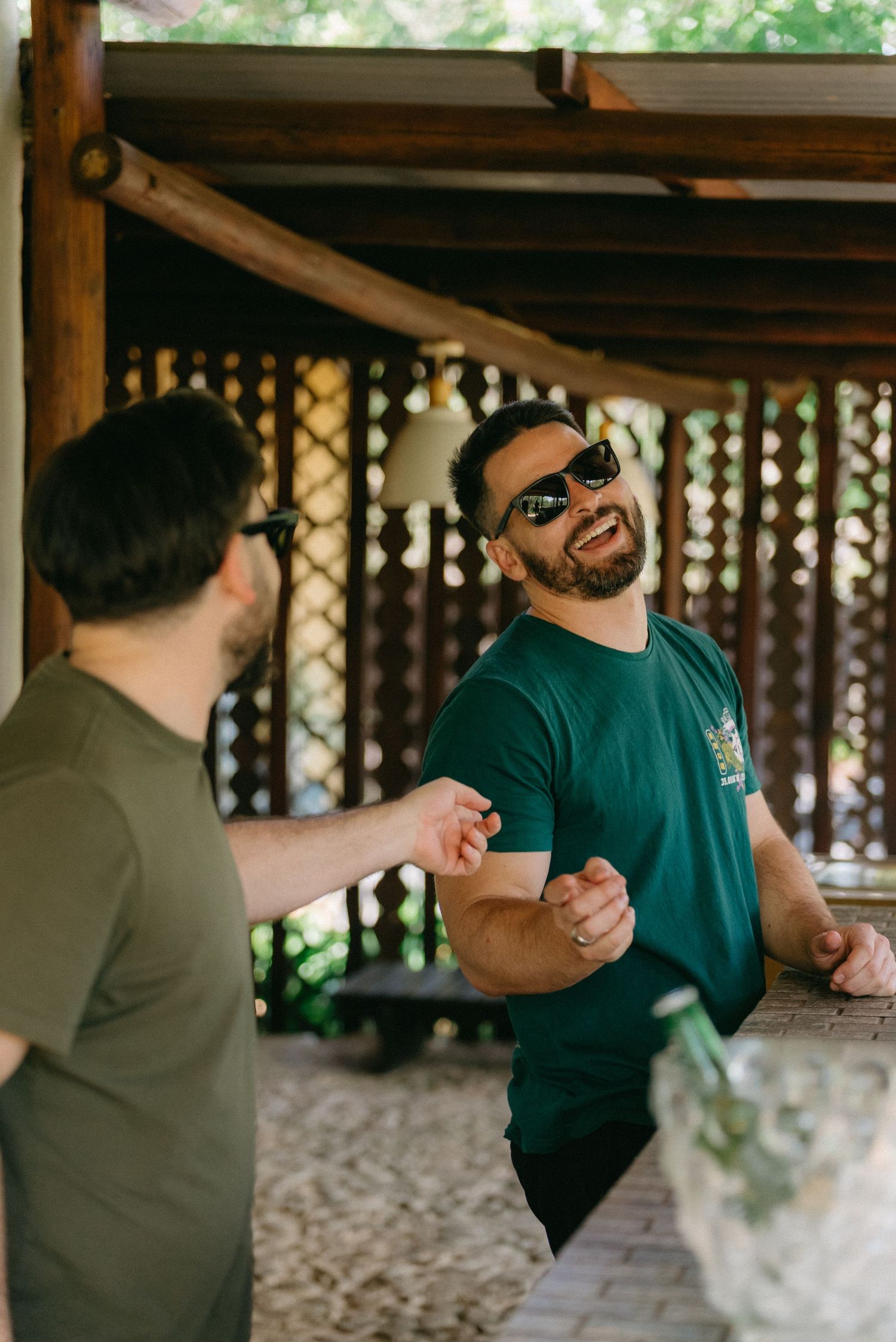 Casual gathering under covered patio with people laughing and socializing.