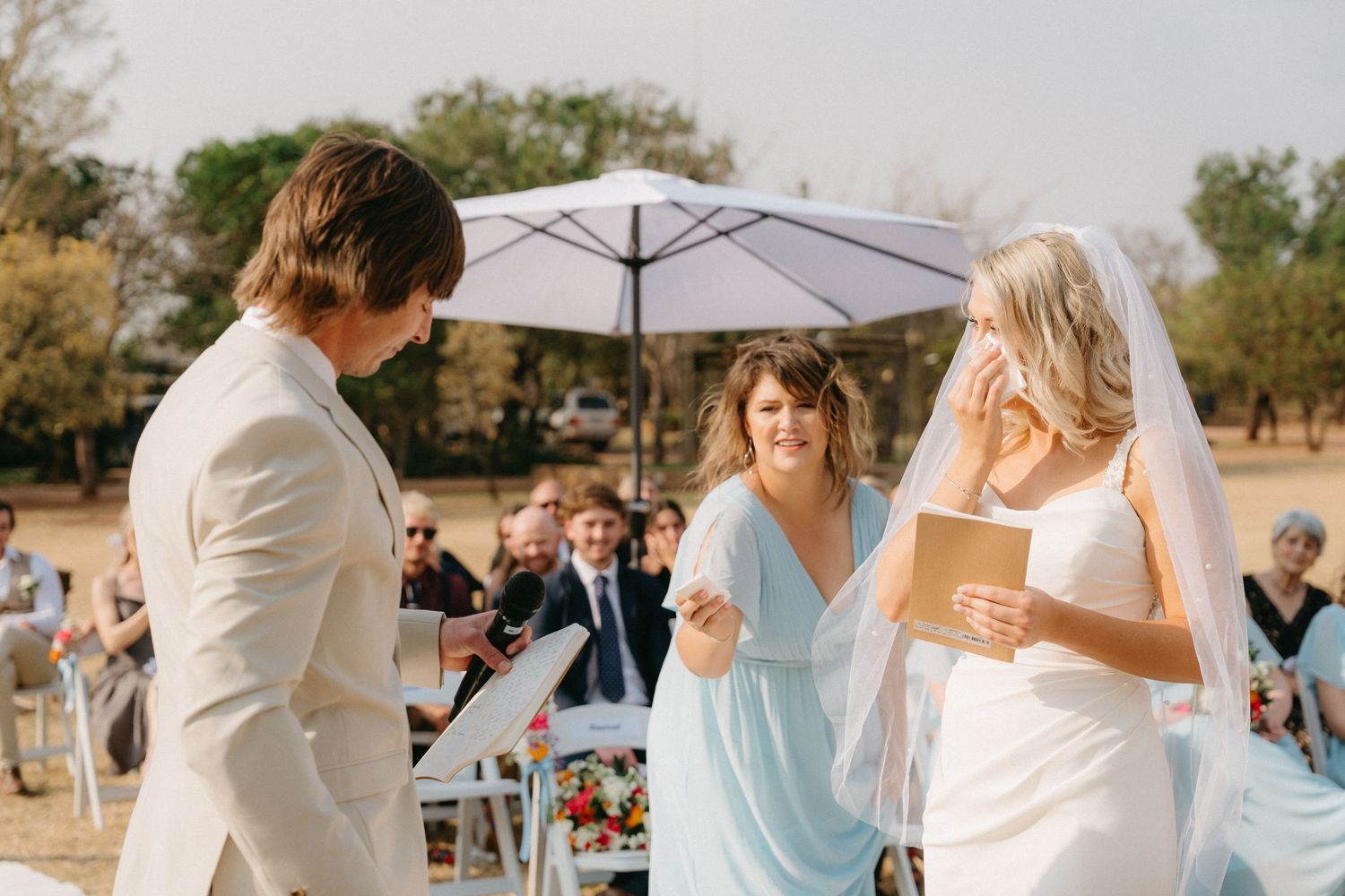 Wedding celebration under white umbrellas with light blue and white color scheme.