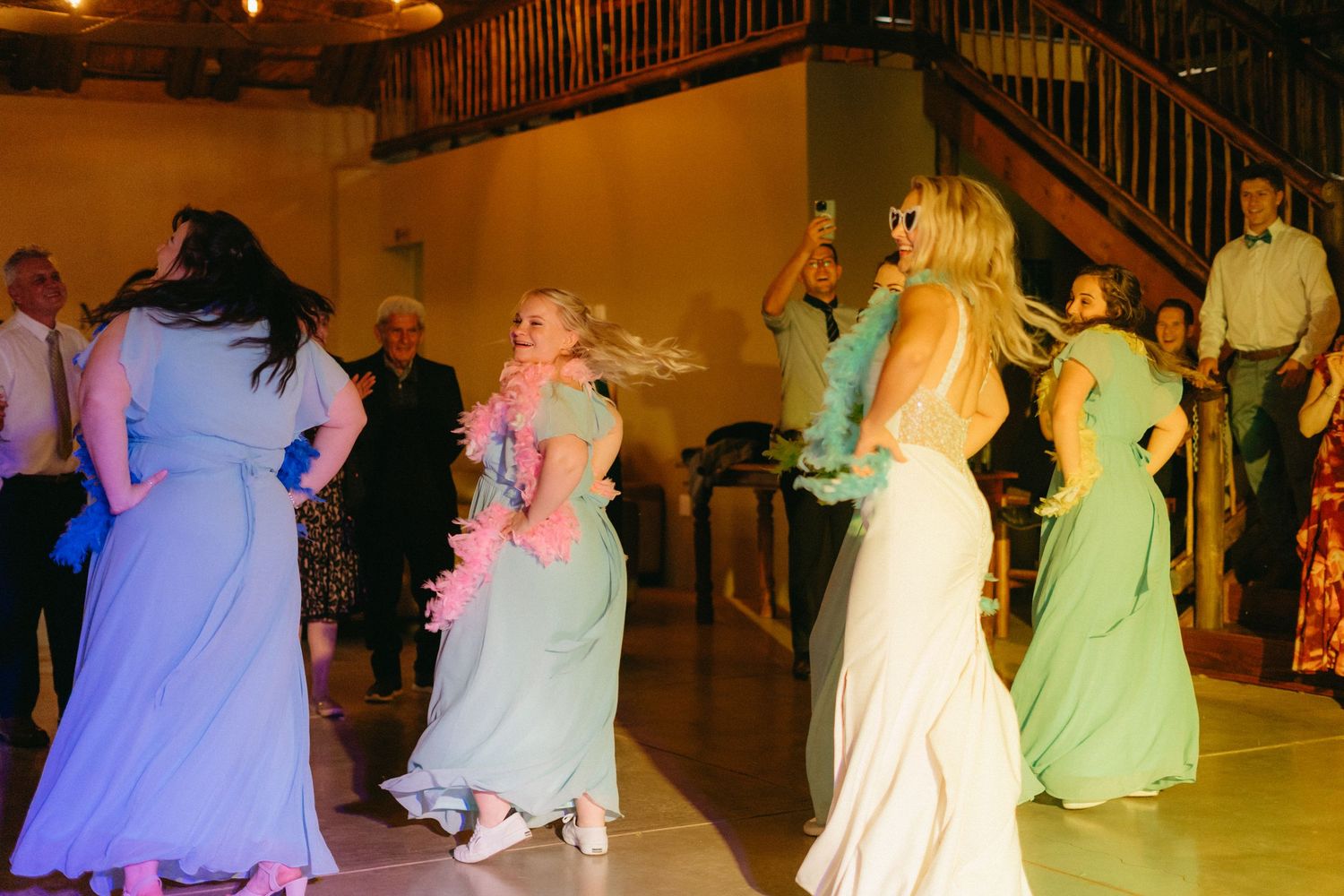 Wedding dance floor illuminated with colorful lights as guests dance in formal dresses.