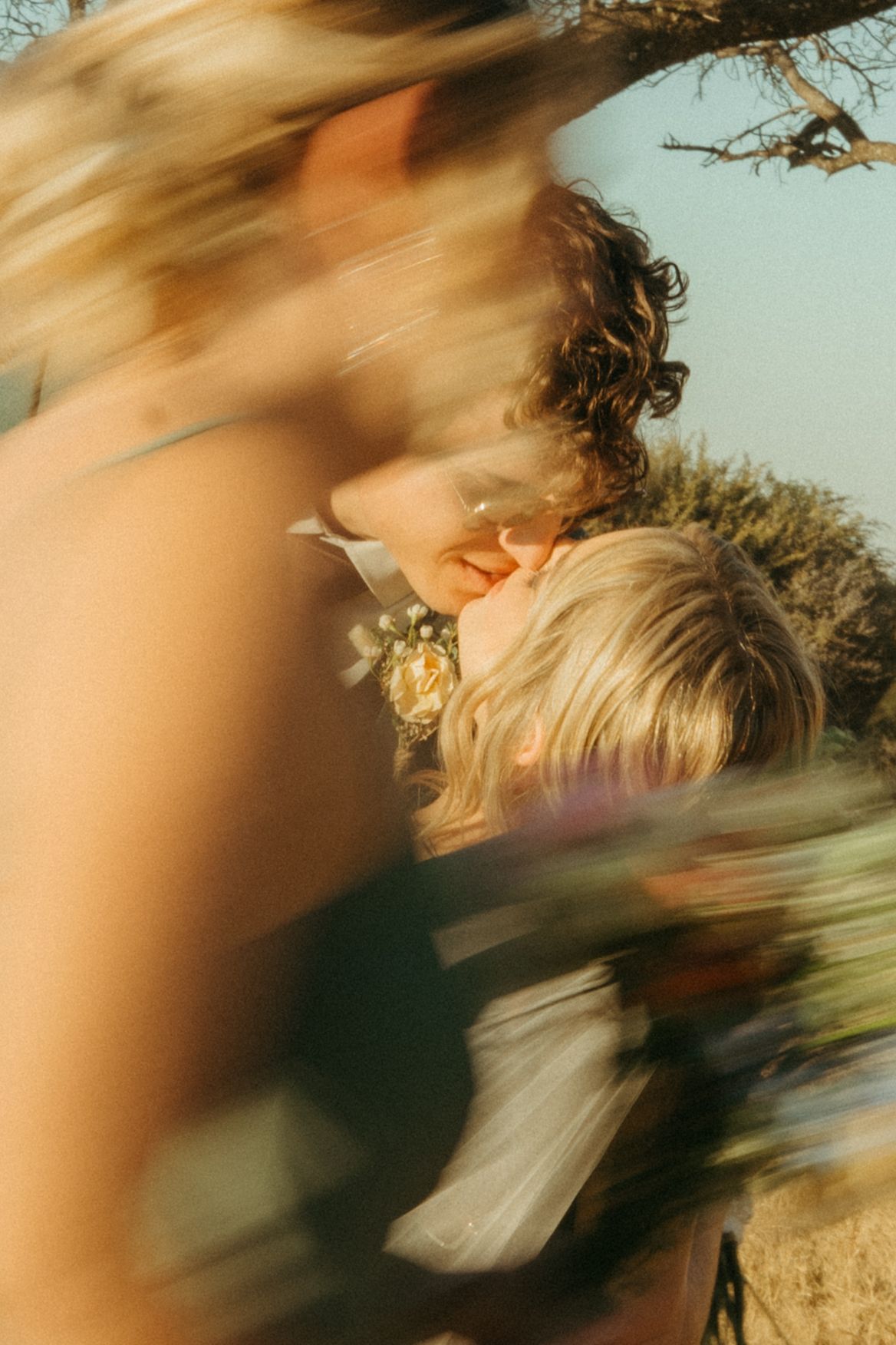 A couple shares a romantic kiss in the Limpopo bushveld, captured with a dreamy blur effect in warm golden light.