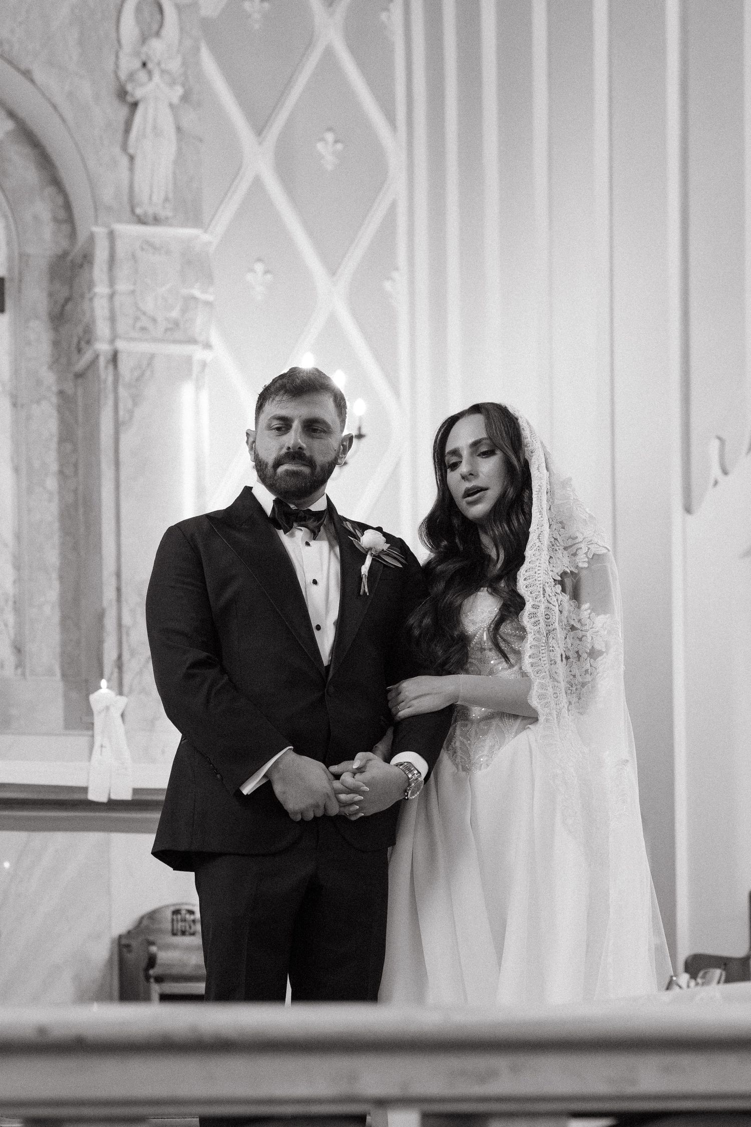 Black and white photo of a bride and groom standing at the altar during their Rosebank Catholic Church wedding ceremony.