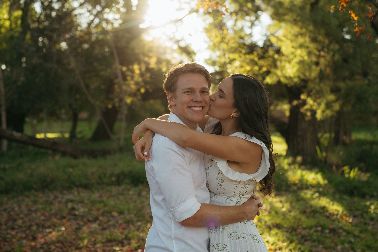 A couple shares an intimate moment in a sunlit garden during their wedding ceremony.