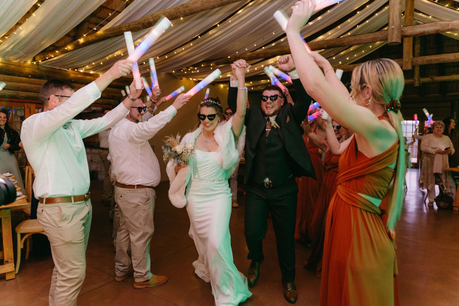 Wedding guests dance and celebrate with glow sticks on the dance floor.